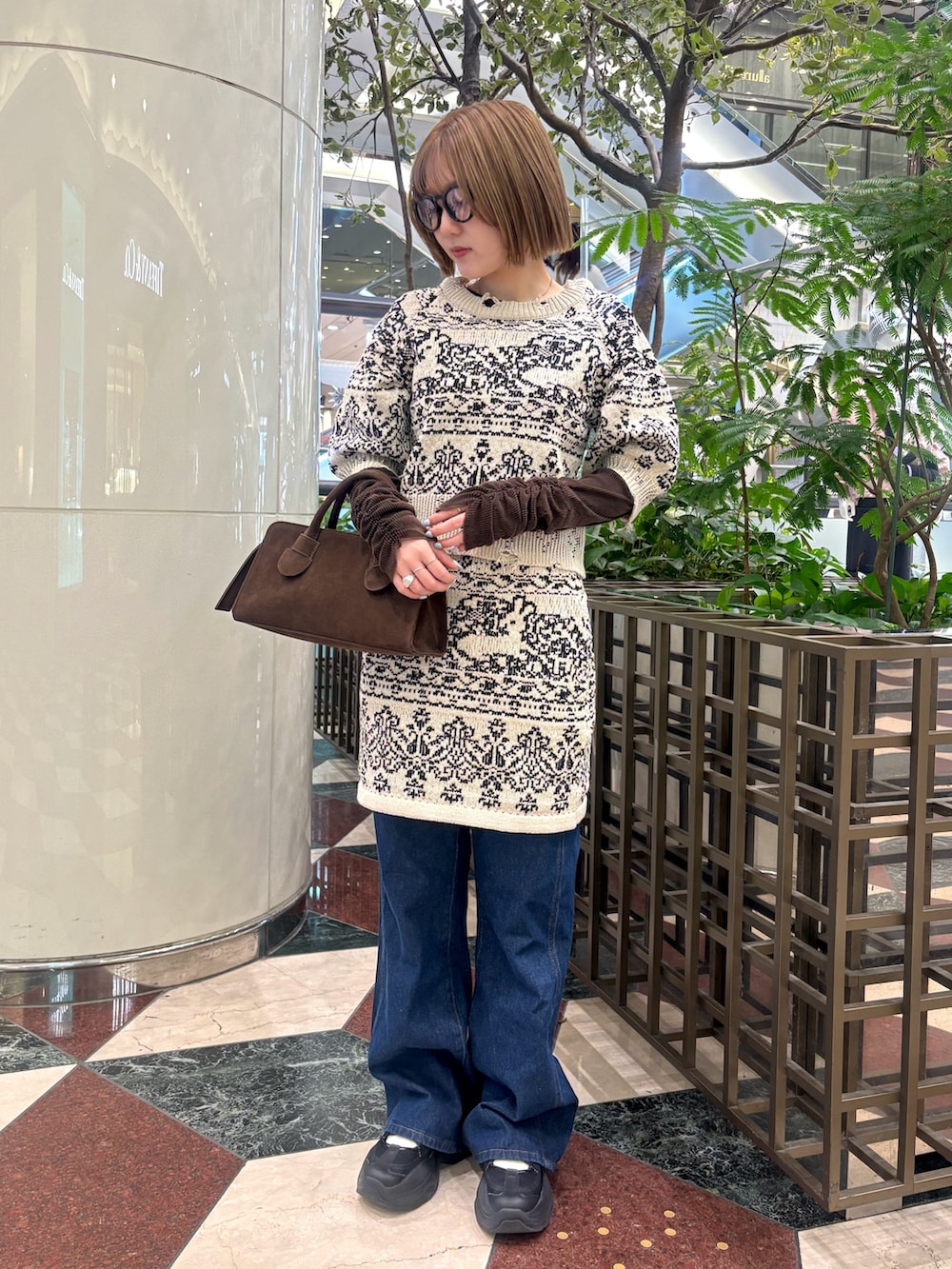 ベージュ系のニット/セーター、ベージュ系のスカート、ブルー系のデニムパンツを着用したレディースの冬コーディネートの2枚目の写真