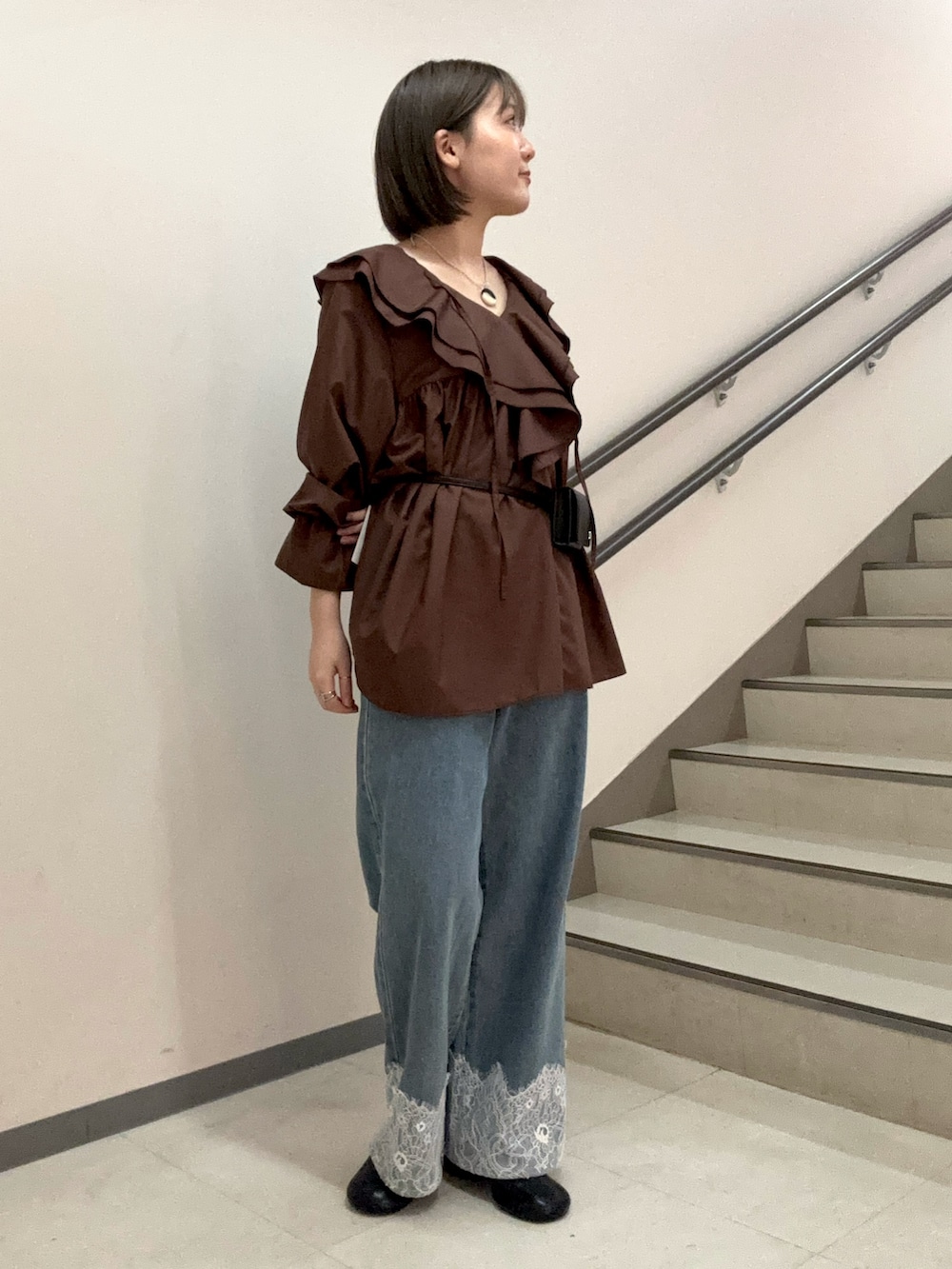ブラウン系のワンピース、ブルー系のデニムパンツ、ブラック系のスリッポンを着用したレディースの夏コーディネートの5枚目の写真