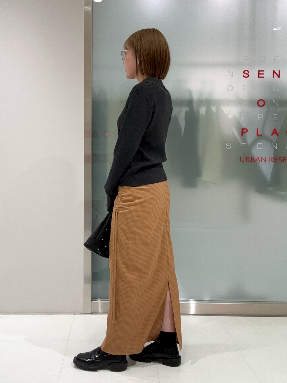 グレー系のカーディガン/ボレロ、ブラック系のハンドバッグ、イエロー系のスカートを着用したレディースの春コーディネートの3枚目の写真