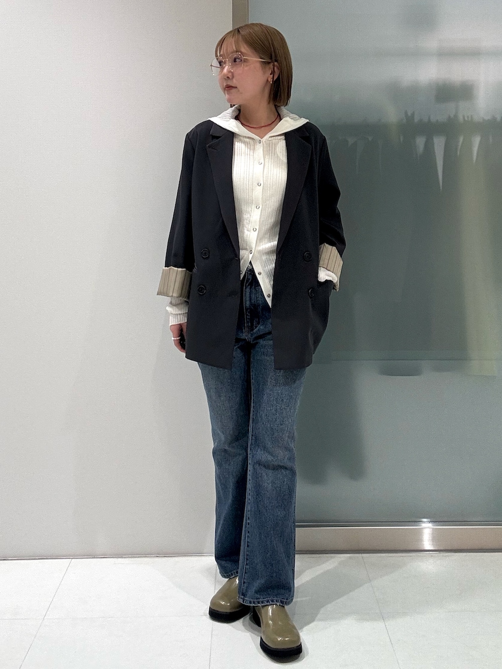 グレー系のテーラードジャケット、ホワイト系のニット/セーター、ブルー系のデニムパンツを着用したレディースの春コーディネートの3枚目の写真