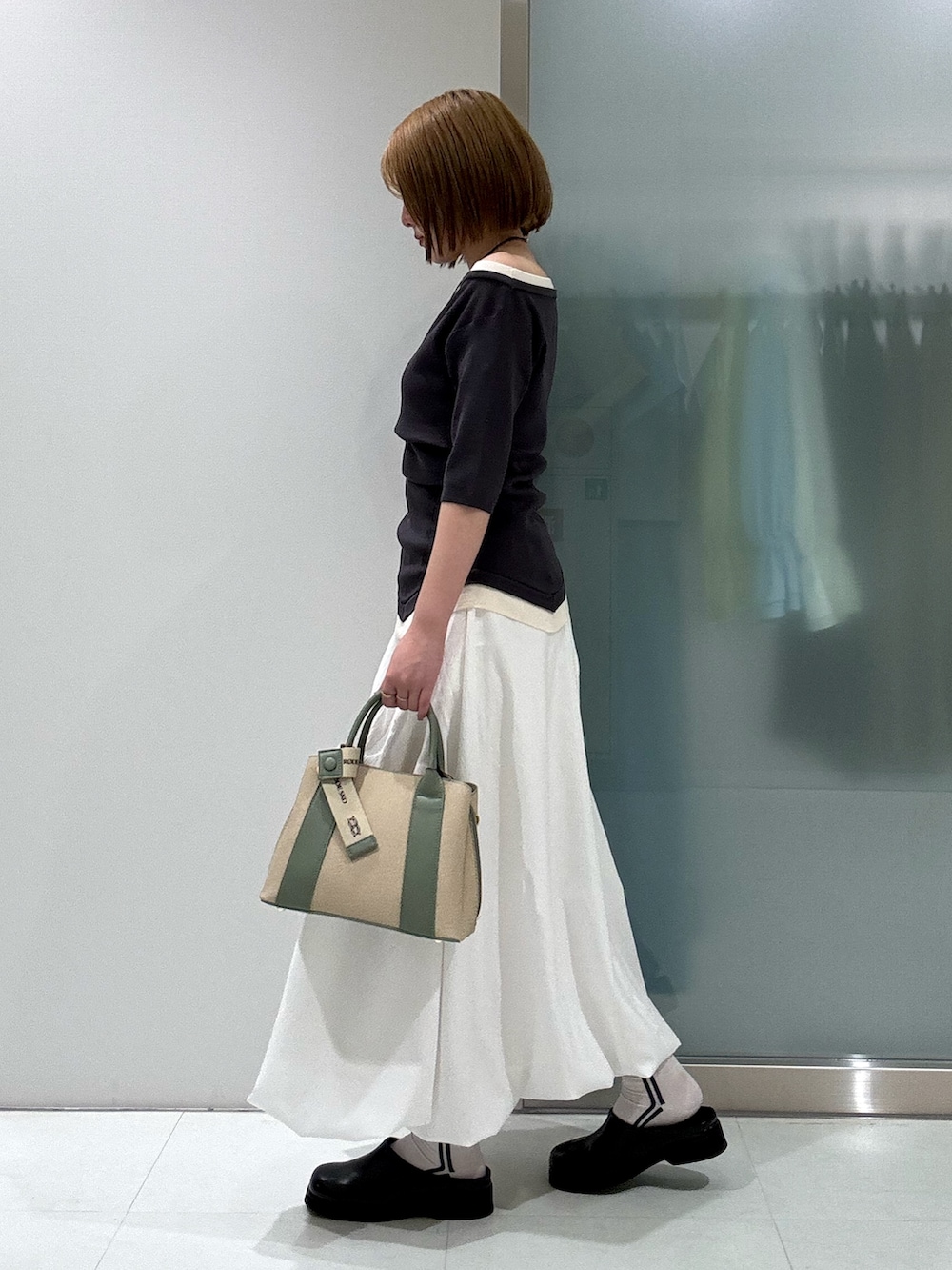 ホワイト系のスカート、ホワイト系のハンドバッグ、ブラック系のサンダルを着用したレディースの春コーディネートの2枚目の写真