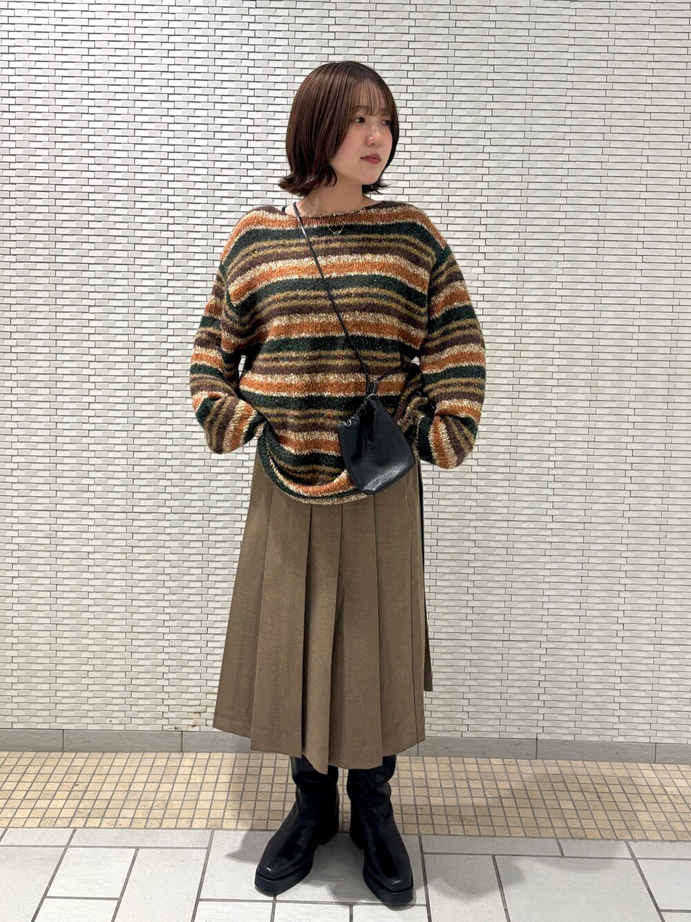 ブラック系のショルダーバッグ、ブラウン系のスカート、ブラウン系のニット/セーターを着用したレディースの秋コーディネートの2枚目の写真