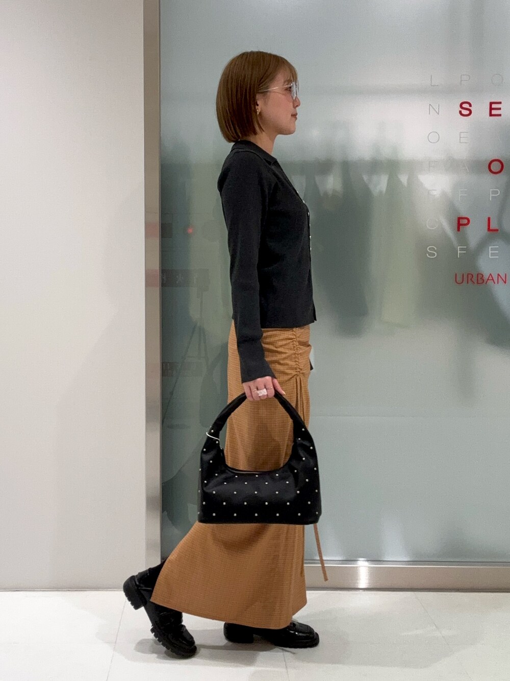 グレー系のカーディガン/ボレロ、ブラック系のハンドバッグ、イエロー系のスカートを着用したレディースの春コーディネートの5枚目の写真