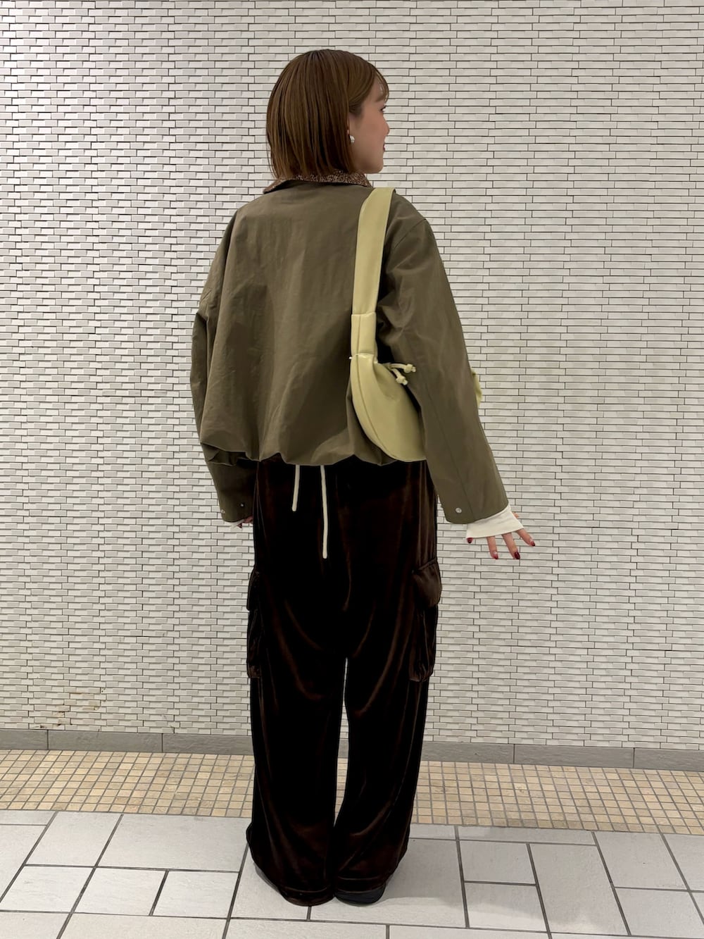 グリーン系のブルゾン、ブラウン系のその他パンツ、ホワイト系のTシャツ/カットソーを着用したレディースの冬コーディネートの3枚目の写真