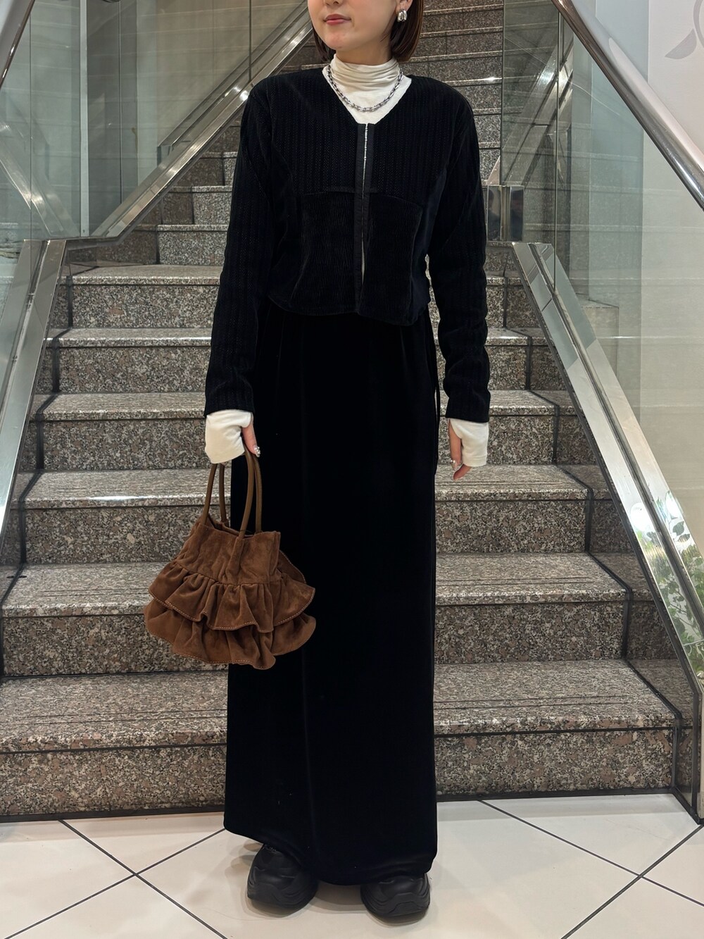 ホワイト系のTシャツ/カットソー、ブラック系のカーディガン/ボレロ、ブラック系のスカートを着用したレディースの冬コーディネートの4枚目の写真