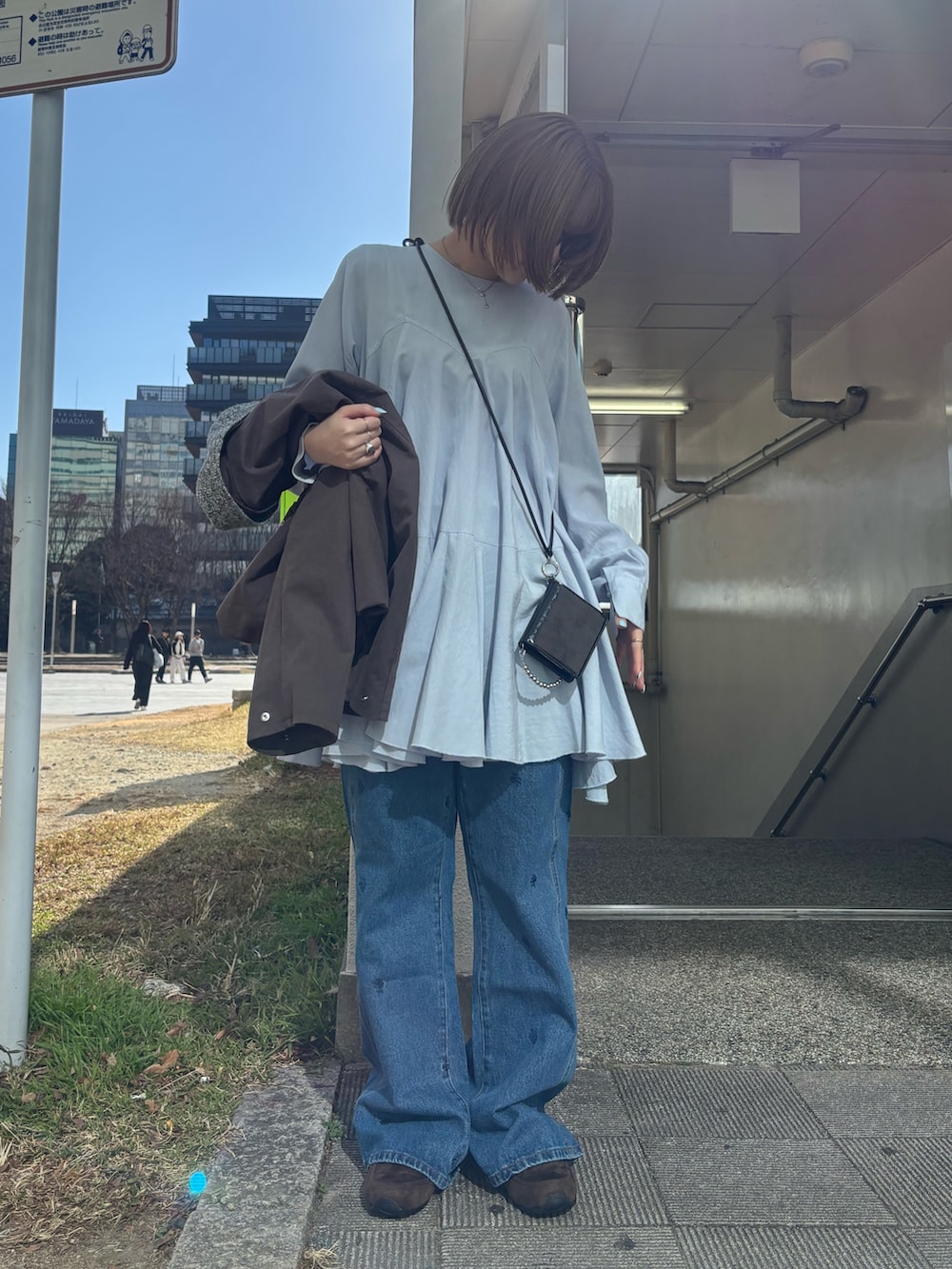 ブラウン系のブルゾン、ブルー系のワンピース、グレー系のスニーカーを着用したレディースの冬コーディネートの5枚目の写真