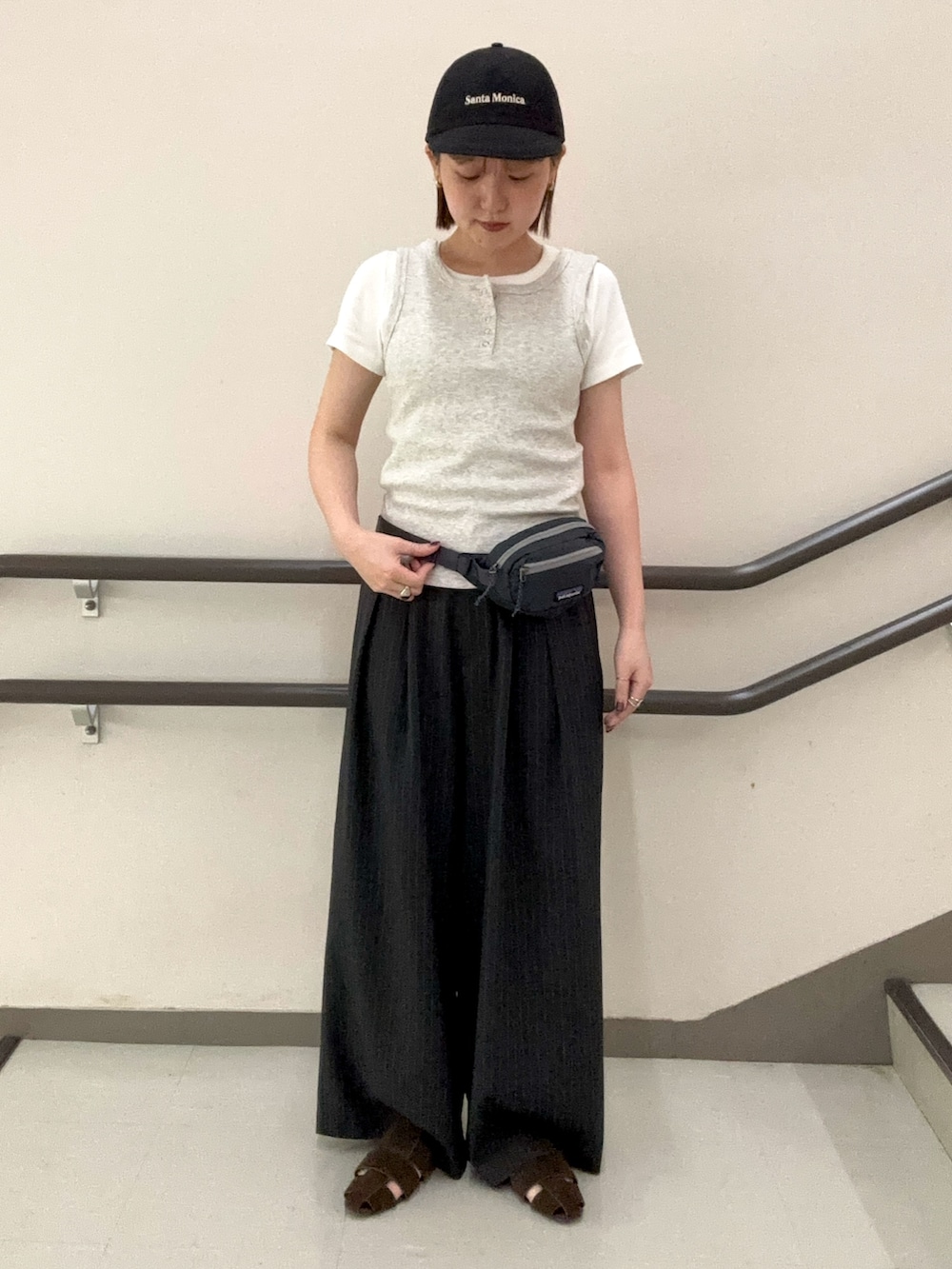 グレー系のタンクトップ、ホワイト系のTシャツ/カットソー、グレー系のスラックスを着用したレディースの夏コーディネートの3枚目の写真