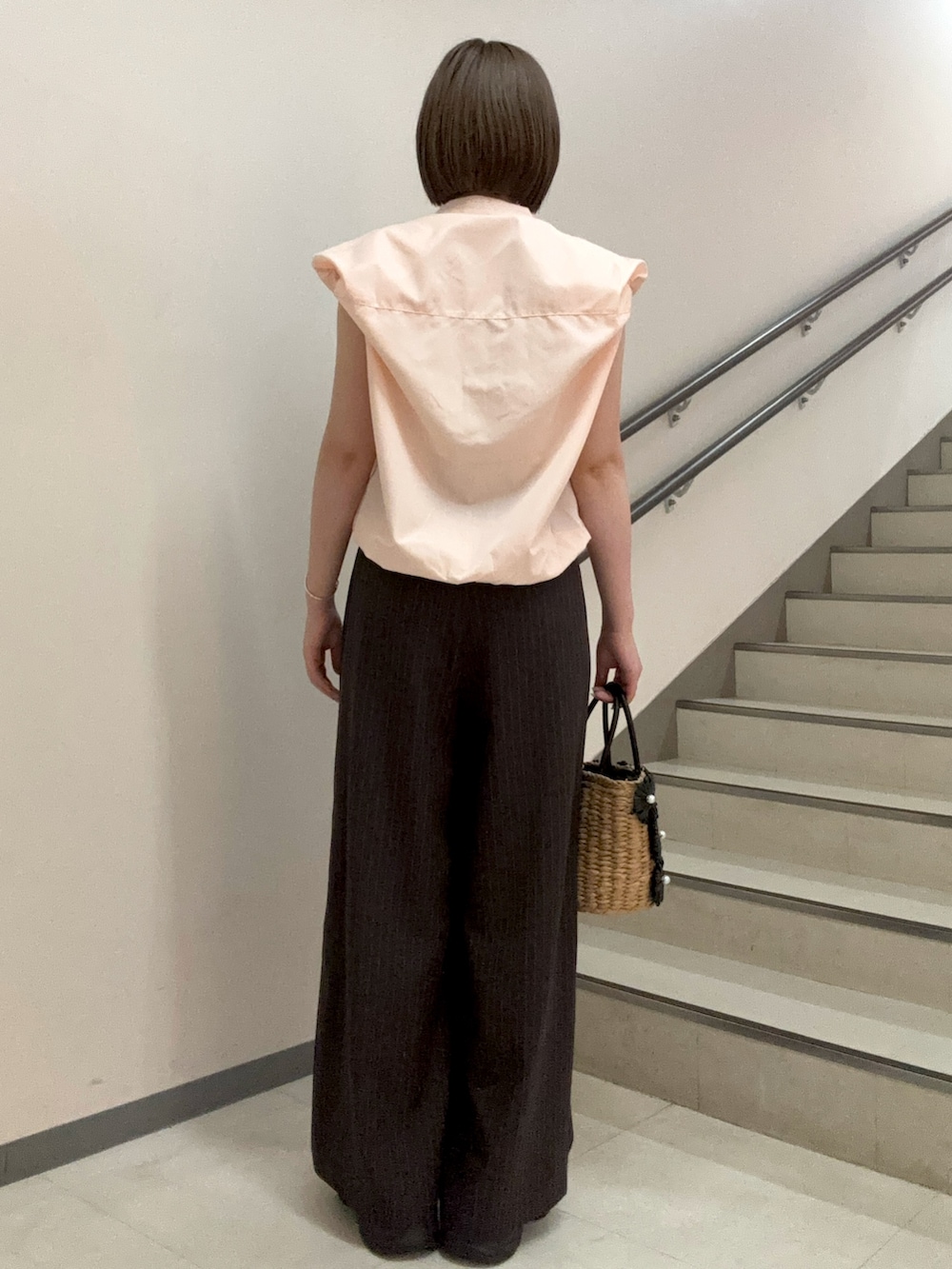 ピンク系のシャツ/ブラウス、ブラウン系のスラックス、ブラック系のショルダーバッグを着用したレディースの夏コーディネートの3枚目の写真
