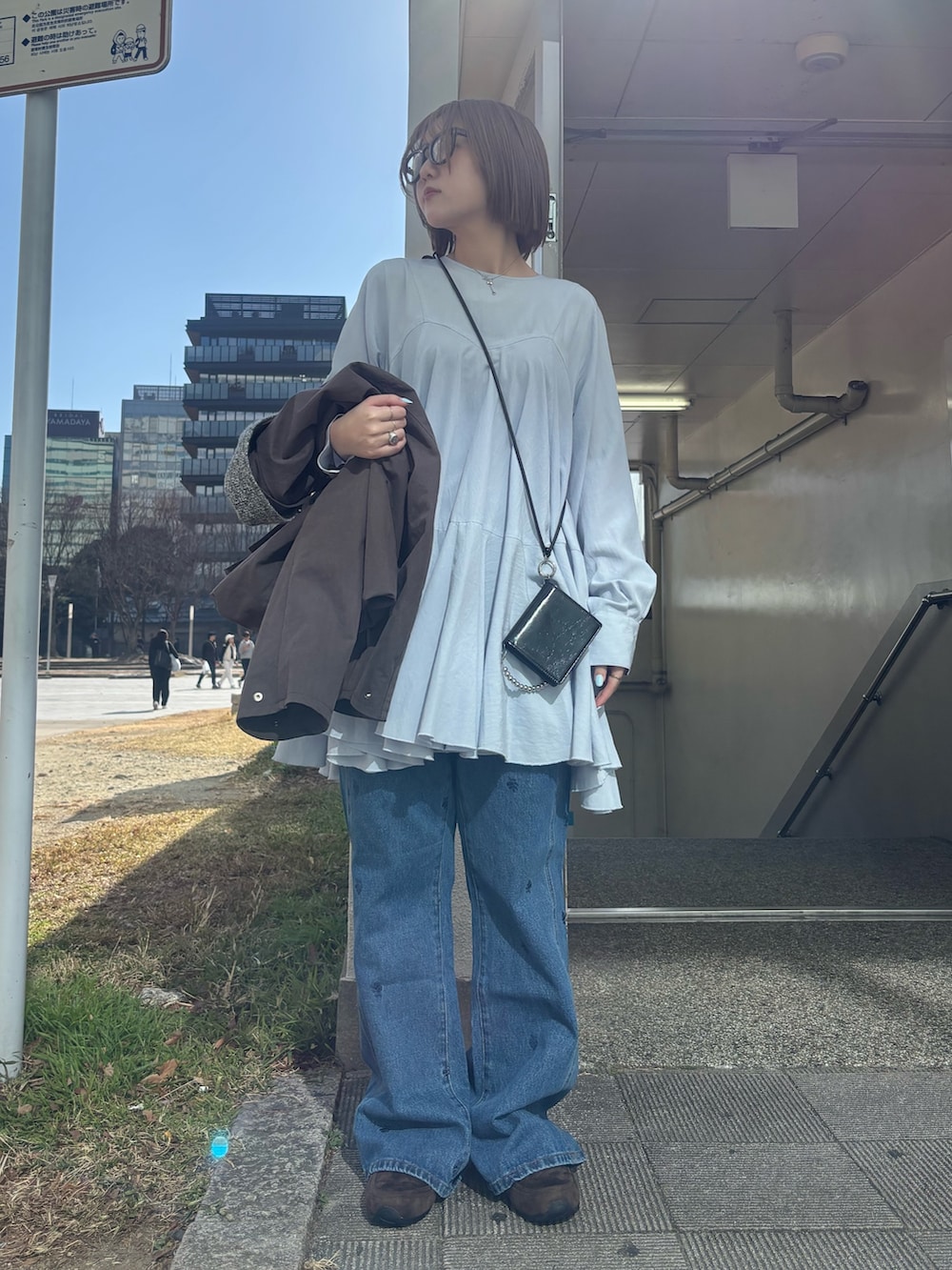 ブラウン系のブルゾン、ブルー系のワンピース、グレー系のスニーカーを着用したレディースの冬コーディネートの4枚目の写真