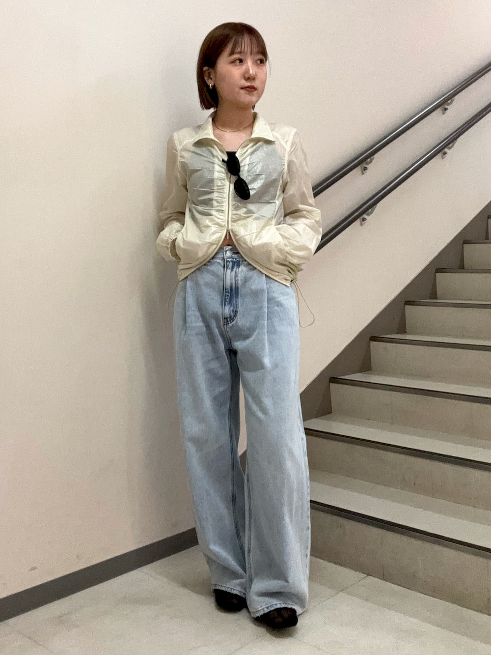 ブルー系のデニムパンツ、ブラック系のキャミソール、ホワイト系のブルゾンを着用したレディースの春コーディネートの5枚目の写真