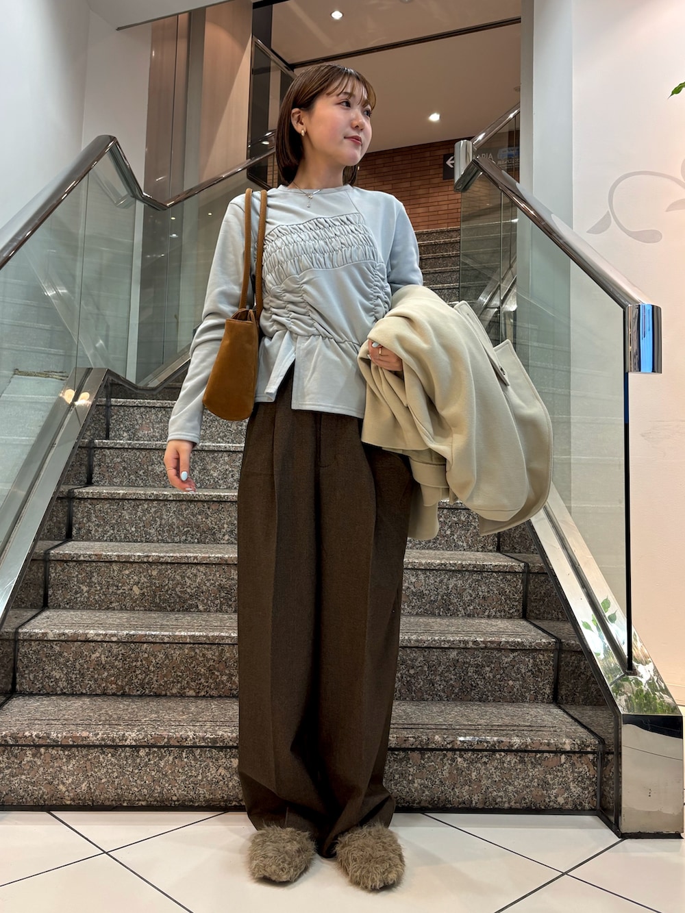 ブルー系のTシャツ/カットソー、イエロー系のボストンバッグ、ベージュ系のその他アウターを着用したレディースの冬コーディネートの3枚目の写真