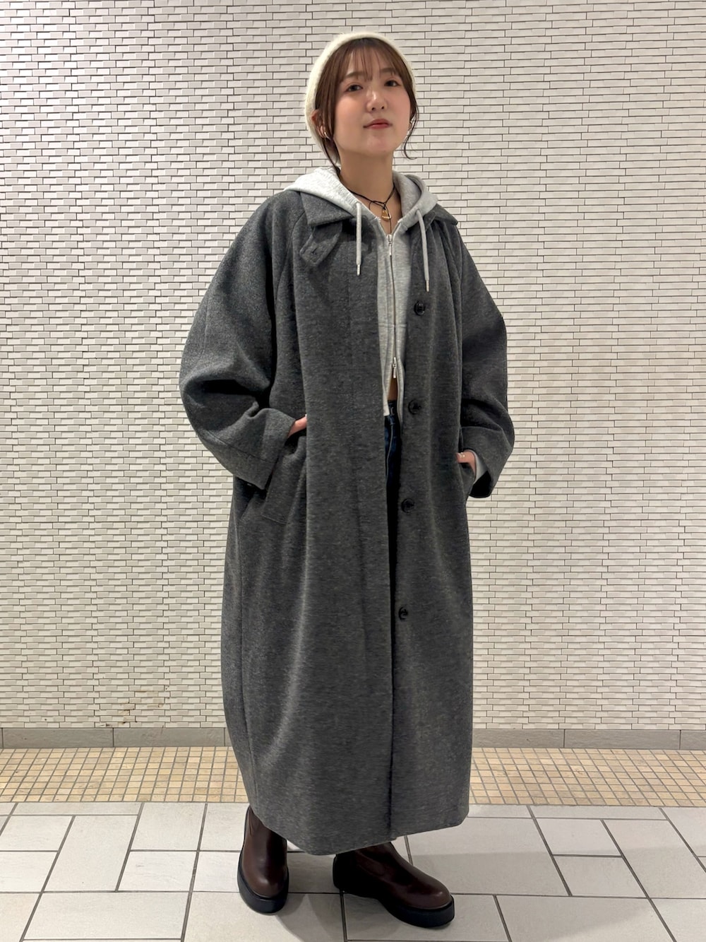 ブルー系のデニムパンツ、ブラウン系のブーツ、グレー系のパーカーを着用したレディースの秋コーディネートの4枚目の写真