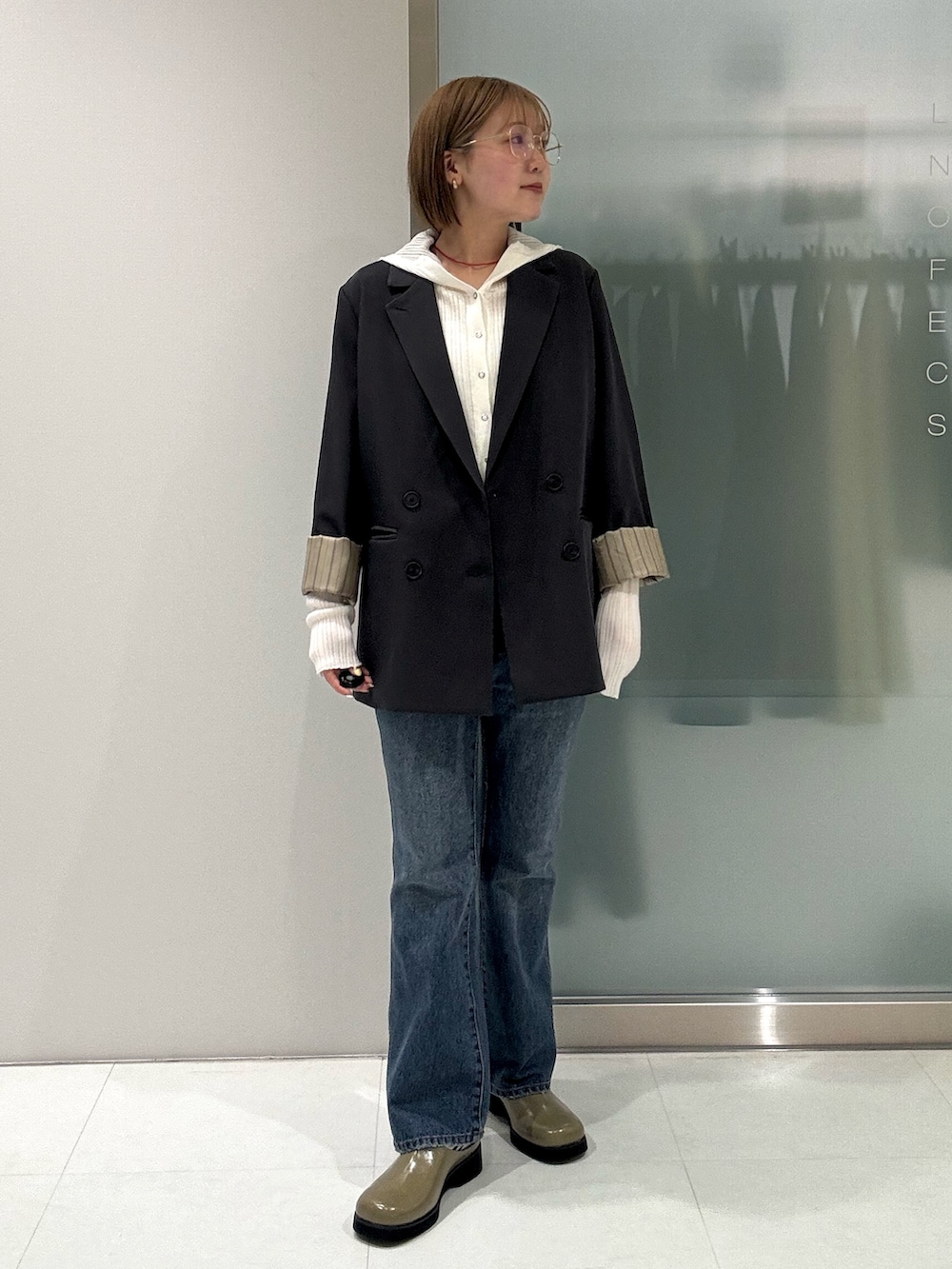 グレー系のテーラードジャケット、ホワイト系のニット/セーター、ブルー系のデニムパンツを着用したレディースの春コーディネートの4枚目の写真