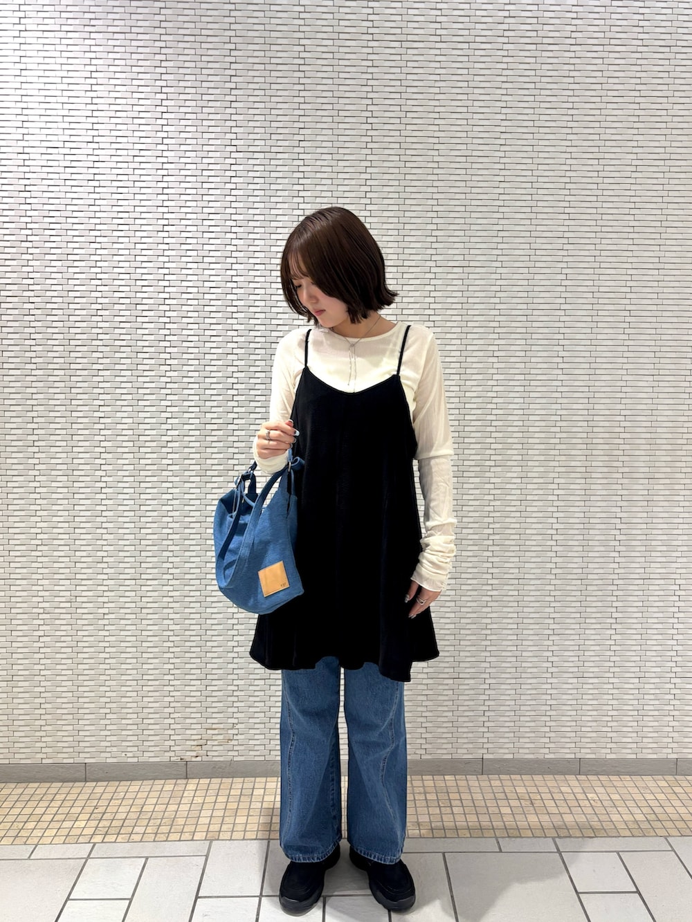 ホワイト系のTシャツ/カットソー、ブラック系のワンピース、ブルー系のデニムパンツを着用したレディースの秋コーディネートの5枚目の写真