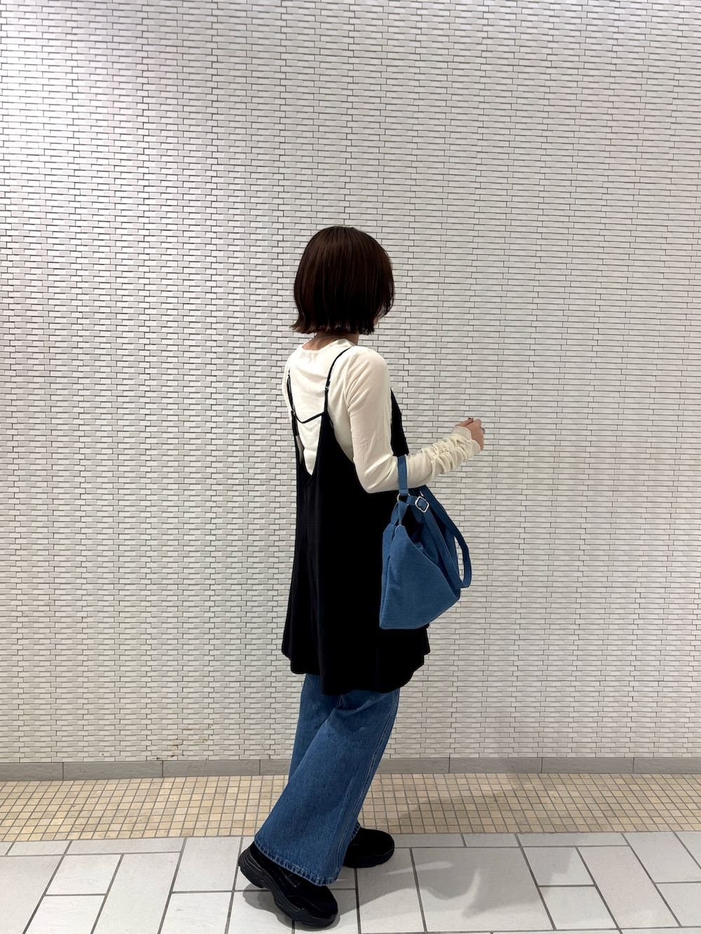 ホワイト系のTシャツ/カットソー、ブラック系のワンピース、ブルー系のデニムパンツを着用したレディースの秋コーディネートの2枚目の写真