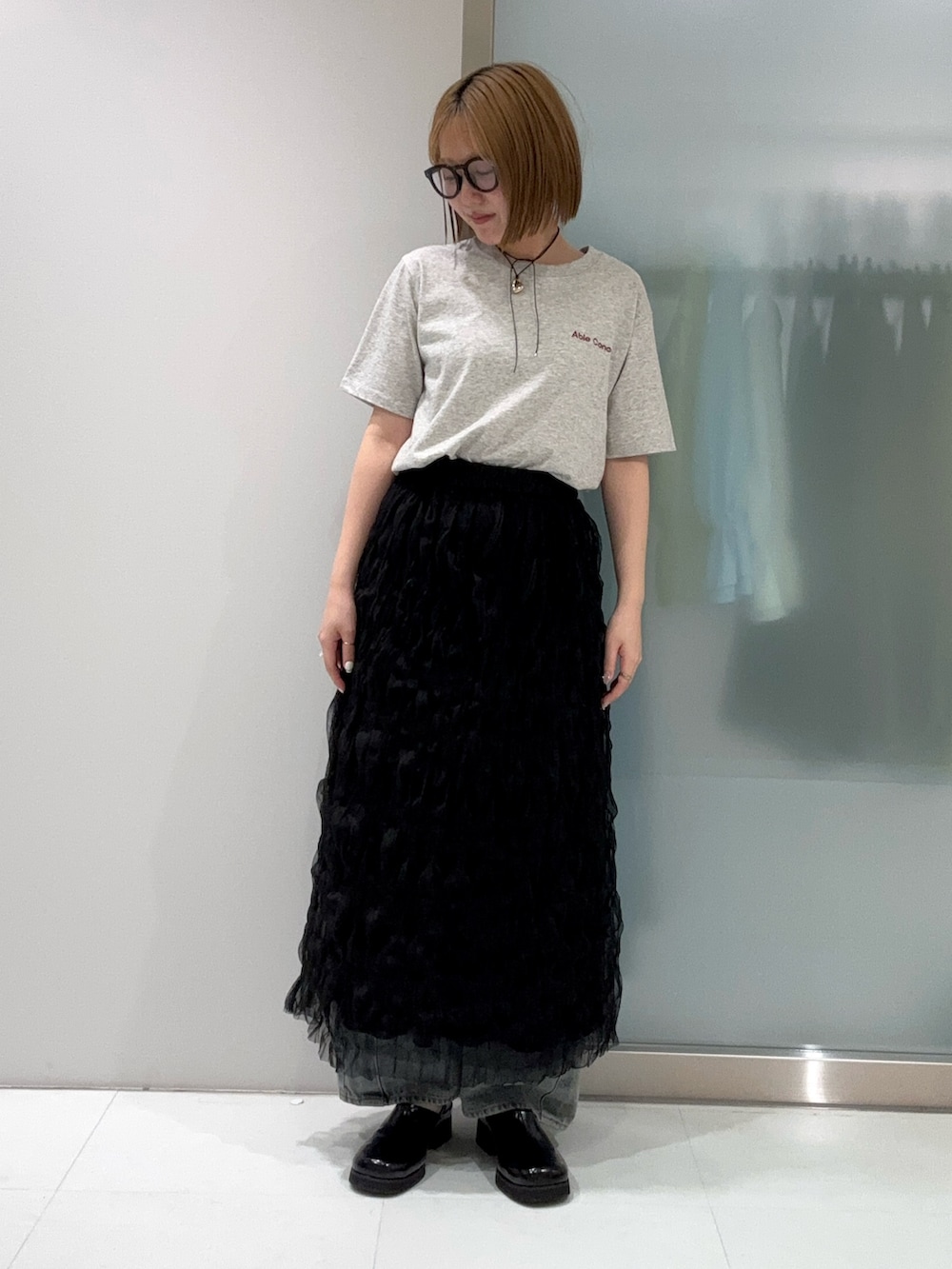 ブルー系のデニムパンツ、ブラック系のスカート、ブラック系のサンダルを着用したレディースの春コーディネートの5枚目の写真