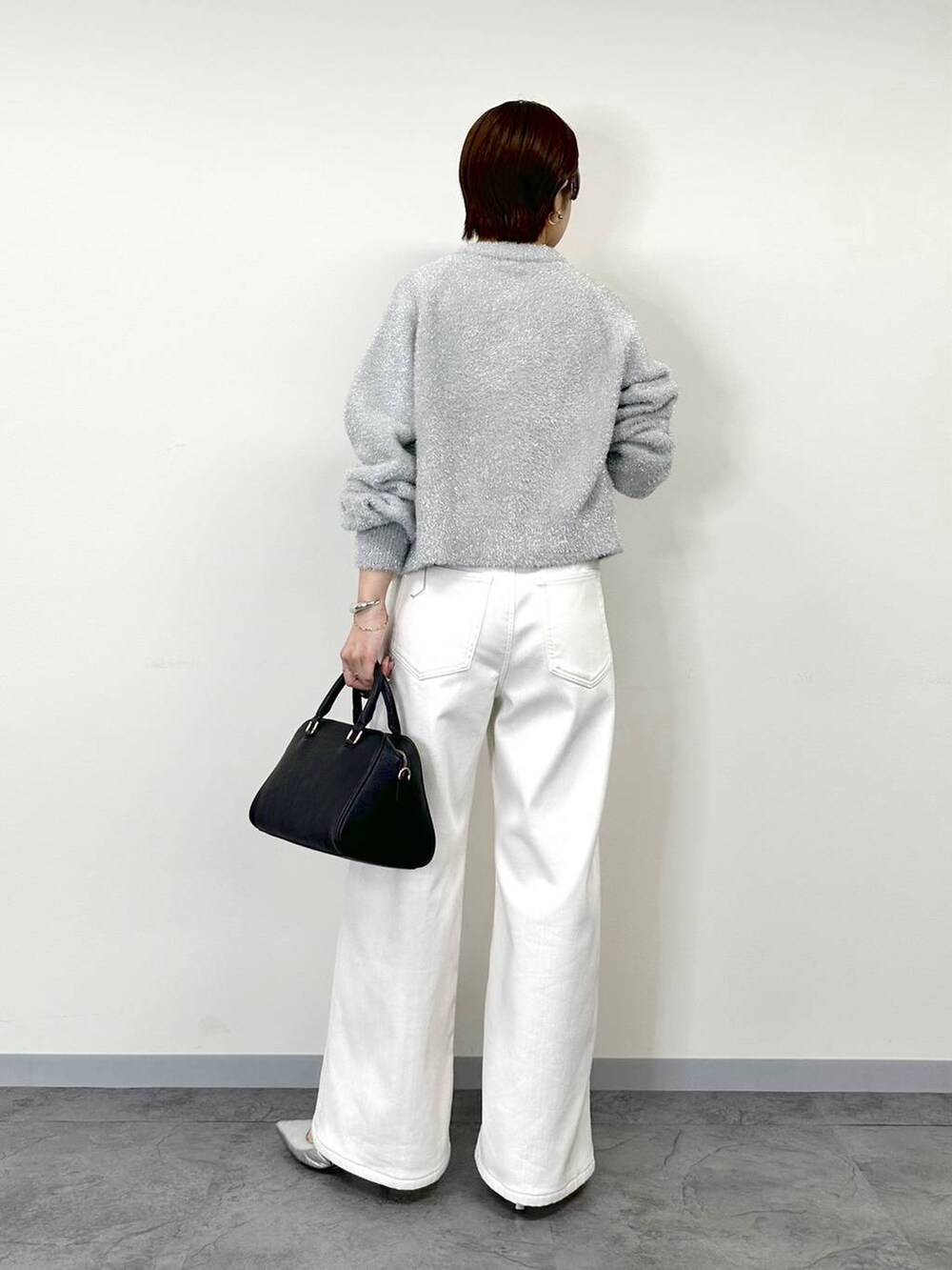 グレー系のニット/セーター、ホワイト系のデニムパンツ、ホワイト系のタンクトップを着用したレディースの秋コーディネートの3枚目の写真