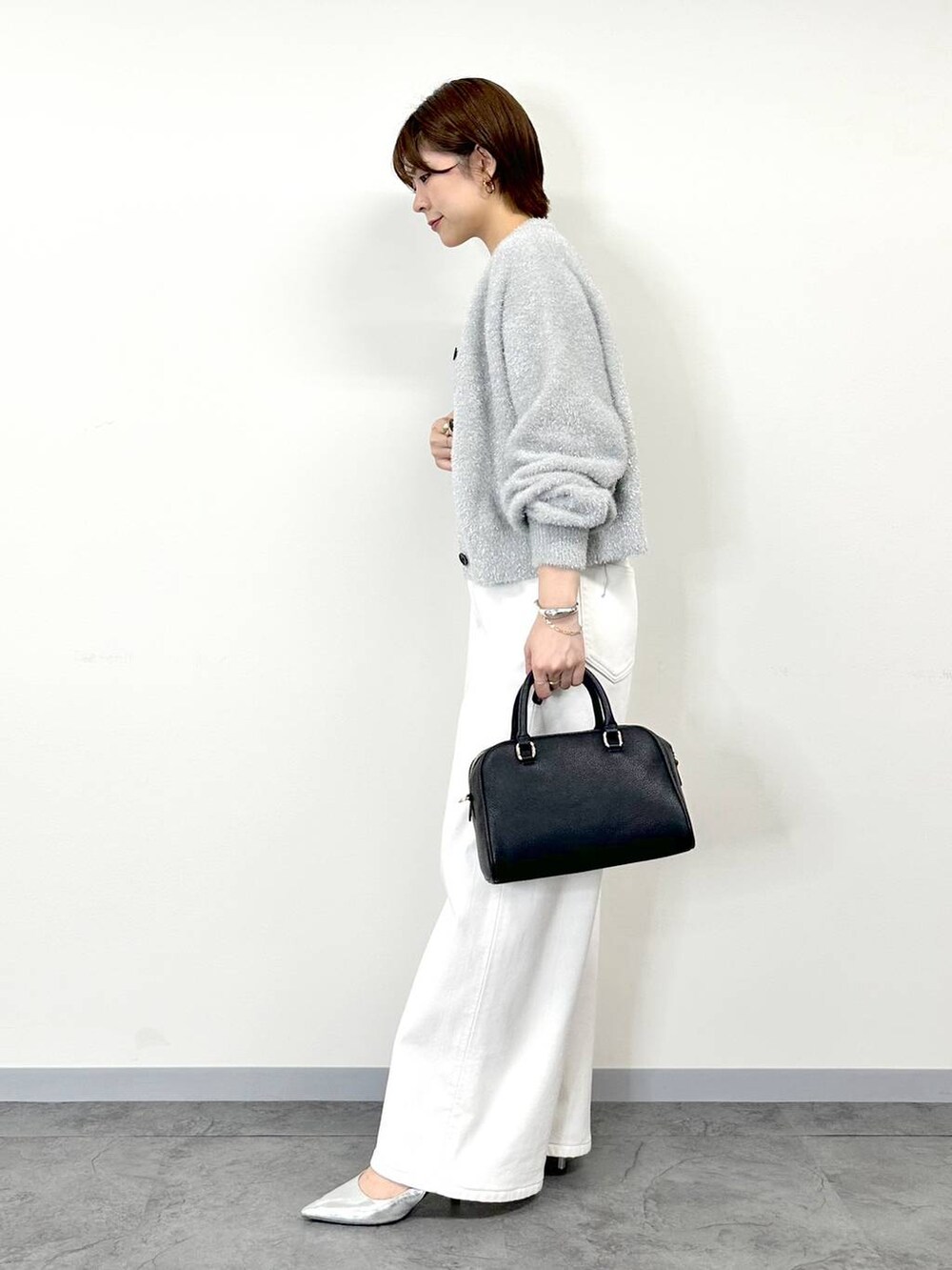 グレー系のニット/セーター、ホワイト系のデニムパンツ、ホワイト系のタンクトップを着用したレディースの秋コーディネートの2枚目の写真