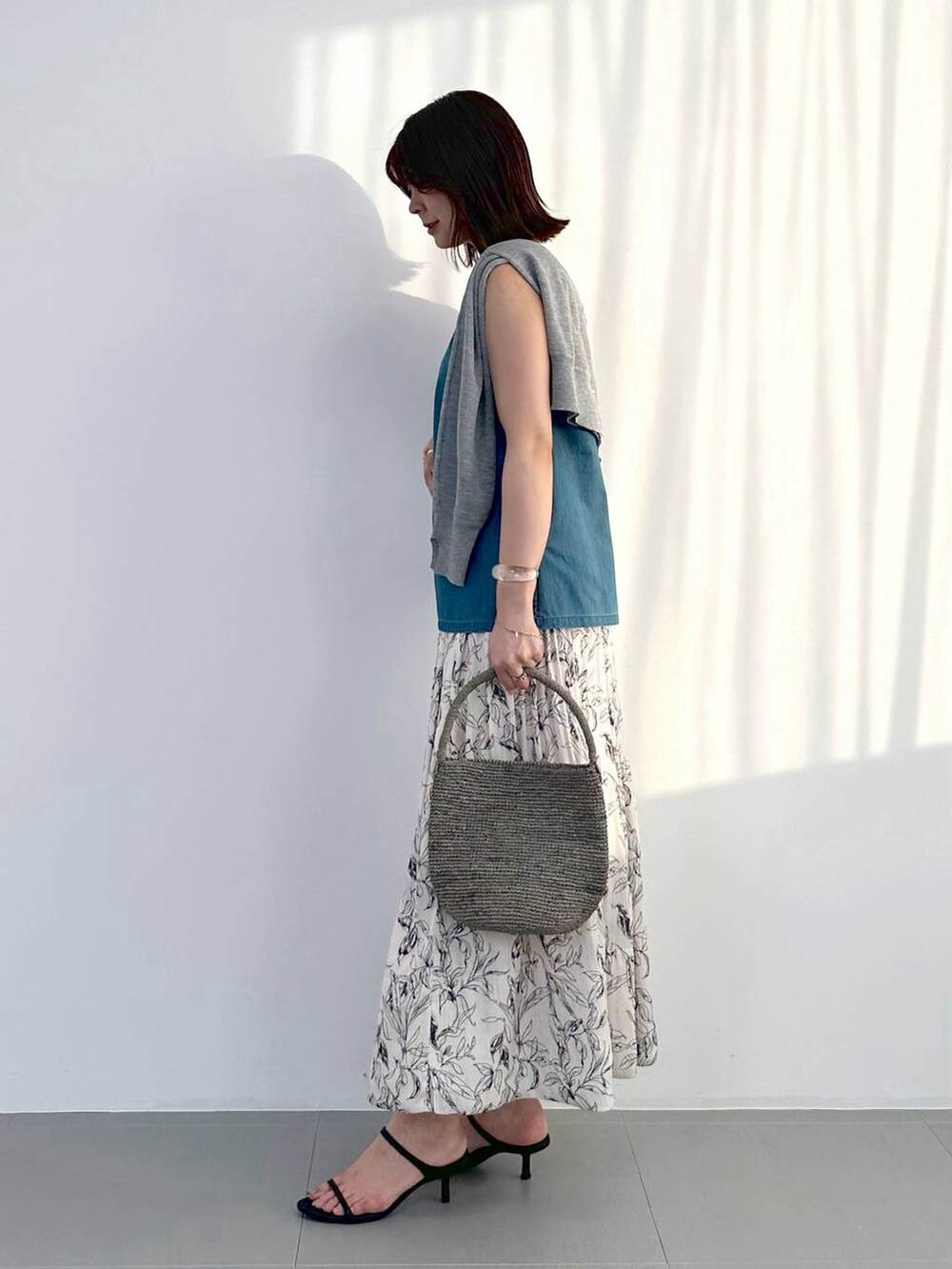 ブラック系のスリッポン、グレー系のトートバッグ、ホワイト系のスカートを着用したレディースの夏コーディネートの2枚目の写真