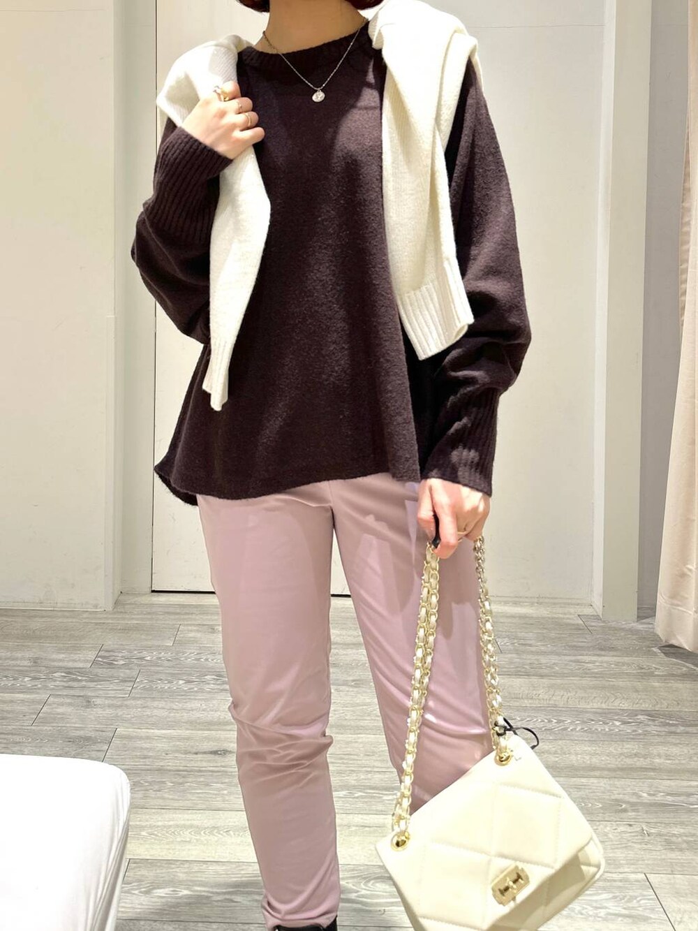 ブラック系のブーツ、ピンク系のスラックス、ホワイト系のショルダーバッグを着用したレディースの冬コーディネートの3枚目の写真