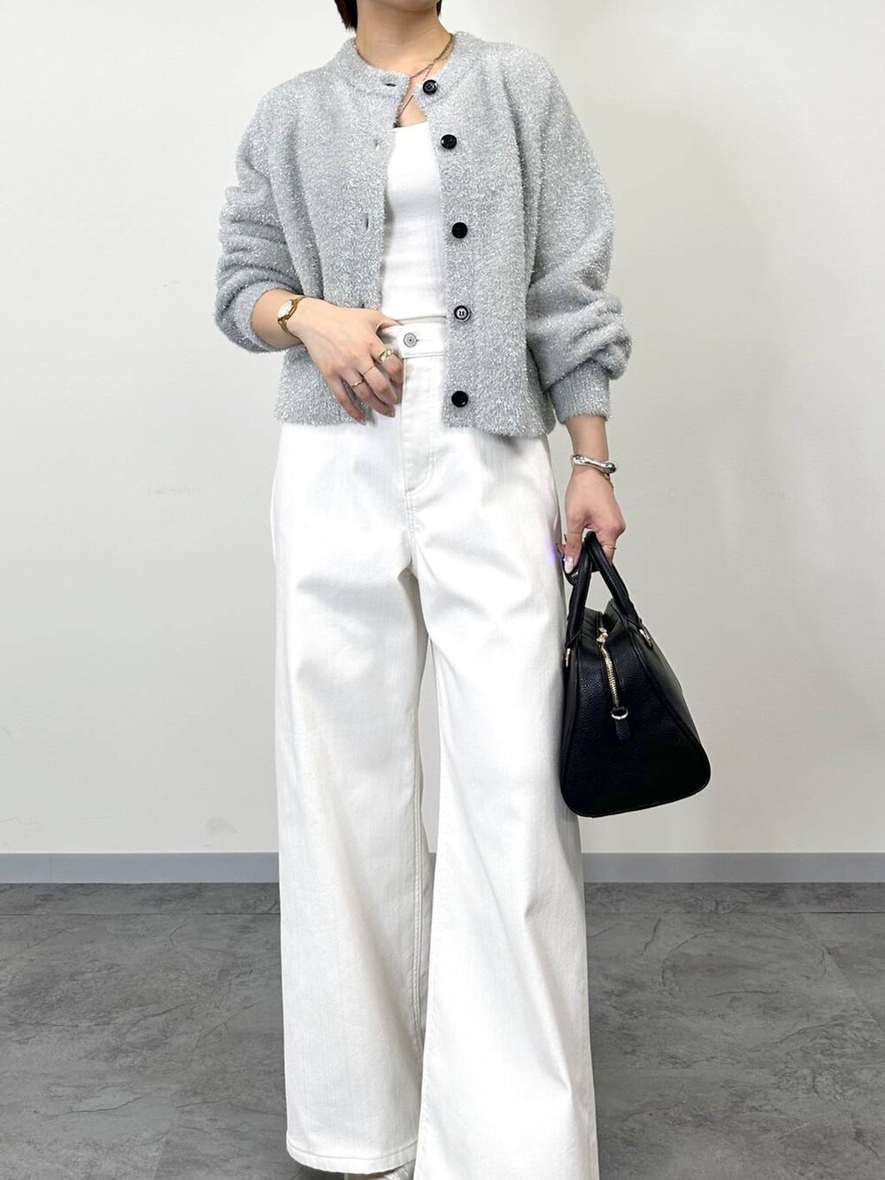 グレー系のニット/セーター、ホワイト系のデニムパンツ、ホワイト系のタンクトップを着用したレディースの秋コーディネートの4枚目の写真