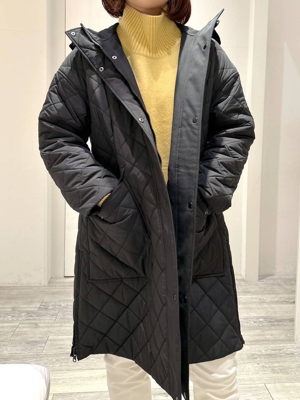 イエロー系のニット/セーター、ホワイト系のその他パンツ、ブラック系のダウンジャケット/コートを着用したレディースの冬コーディネートの3枚目の写真
