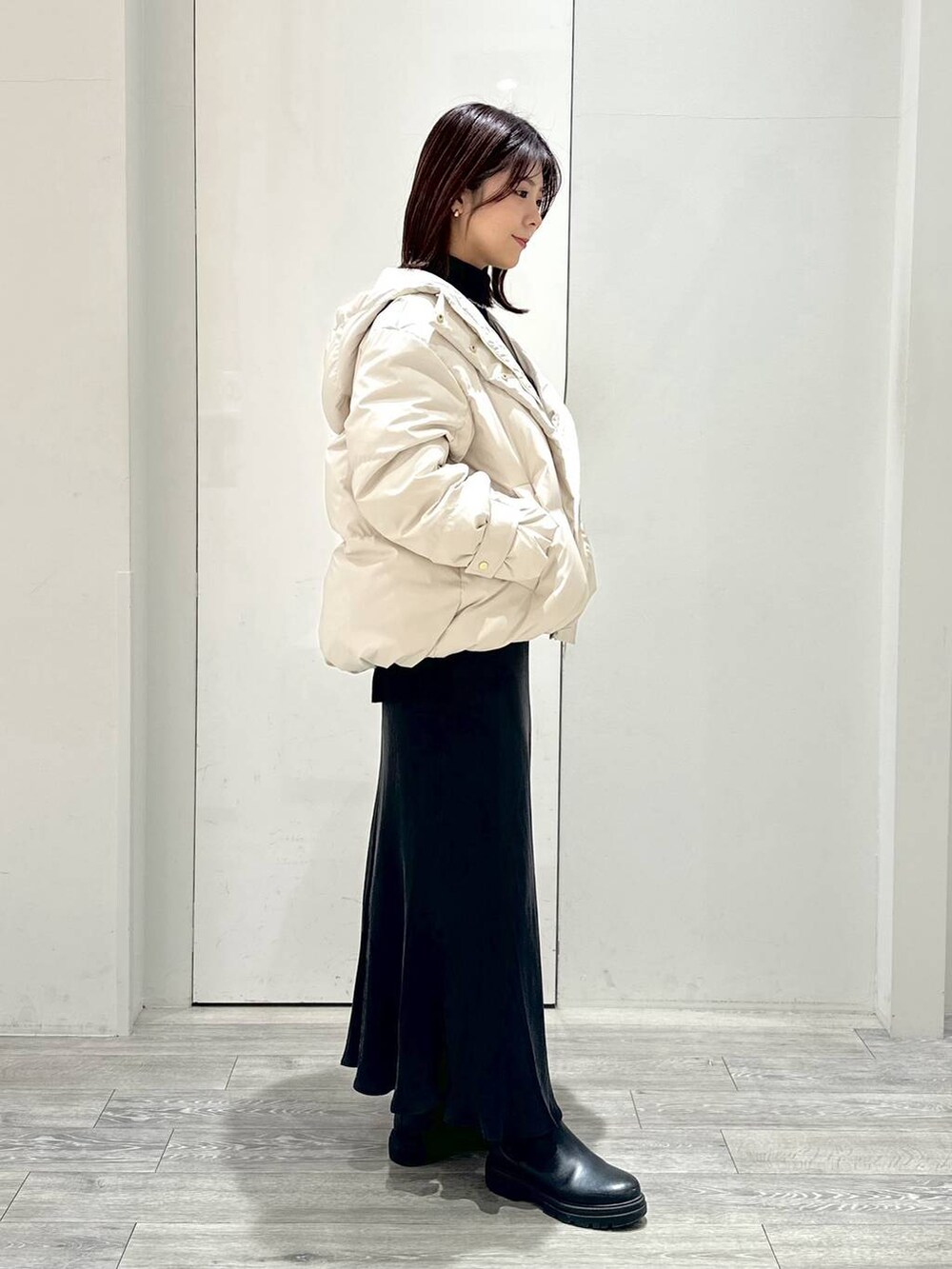 ホワイト系のダウンジャケット/コート、ブラック系のブーツ、ブラック系のニット/セーターを着用したレディースの冬コーディネートの2枚目の写真