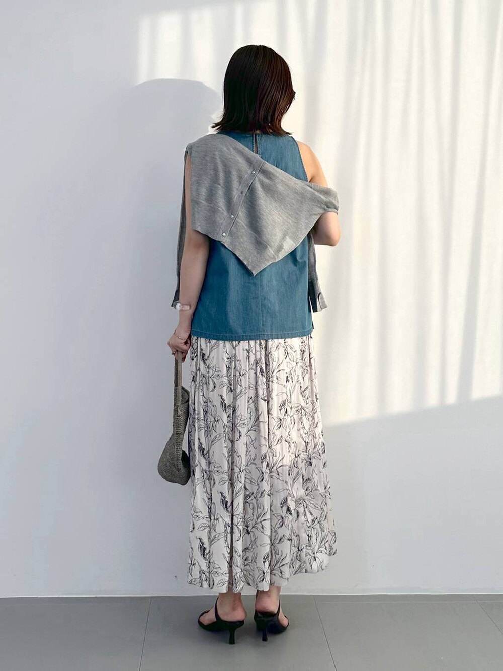 ブラック系のスリッポン、グレー系のトートバッグ、ホワイト系のスカートを着用したレディースの夏コーディネートの3枚目の写真