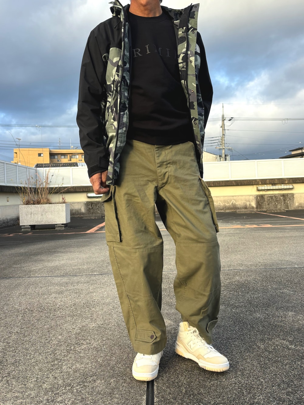 グリーン系のマウンテンパーカー、グリーン系のカーゴパンツ、ホワイト系のスニーカーを着用したメンズの冬コーディネートの2枚目の写真