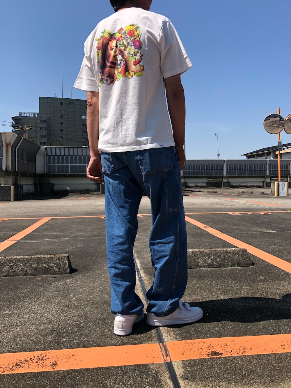ホワイト系のTシャツ/カットソー、ブルー系のチノパンツ、グレー系のスニーカーを着用したメンズの夏コーディネートの2枚目の写真