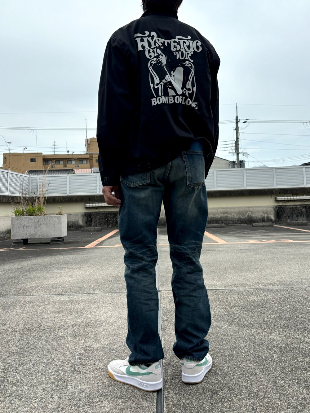 ブラック系のブルゾン、ブラック系のTシャツ/カットソー、ブルー系のデニムパンツを着用したメンズの春コーディネートの2枚目の写真