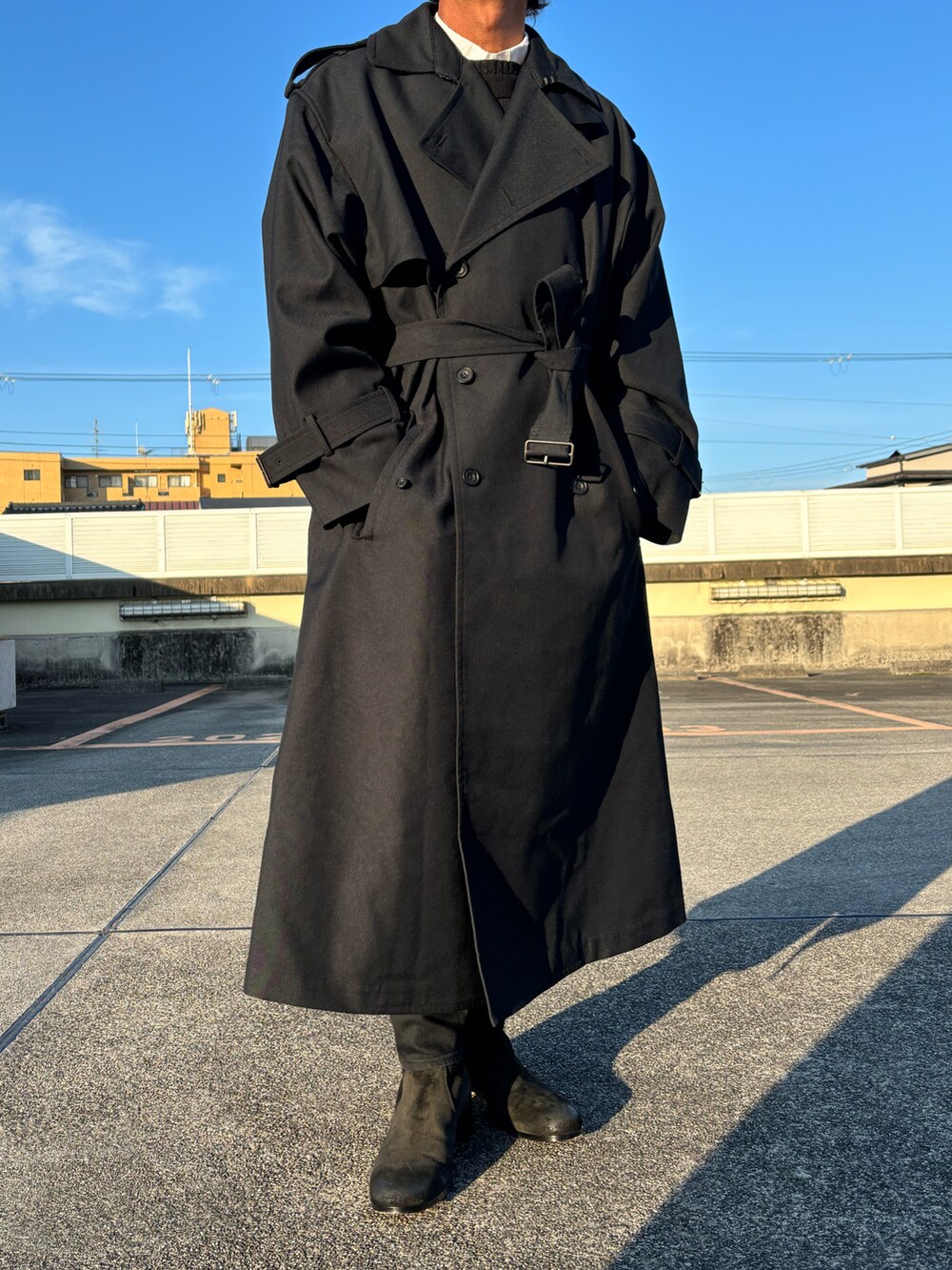 ブラック系のトレンチコート、ブラック系のブーツ、ブラック系のデニムパンツを着用したメンズの冬コーディネートの2枚目の写真