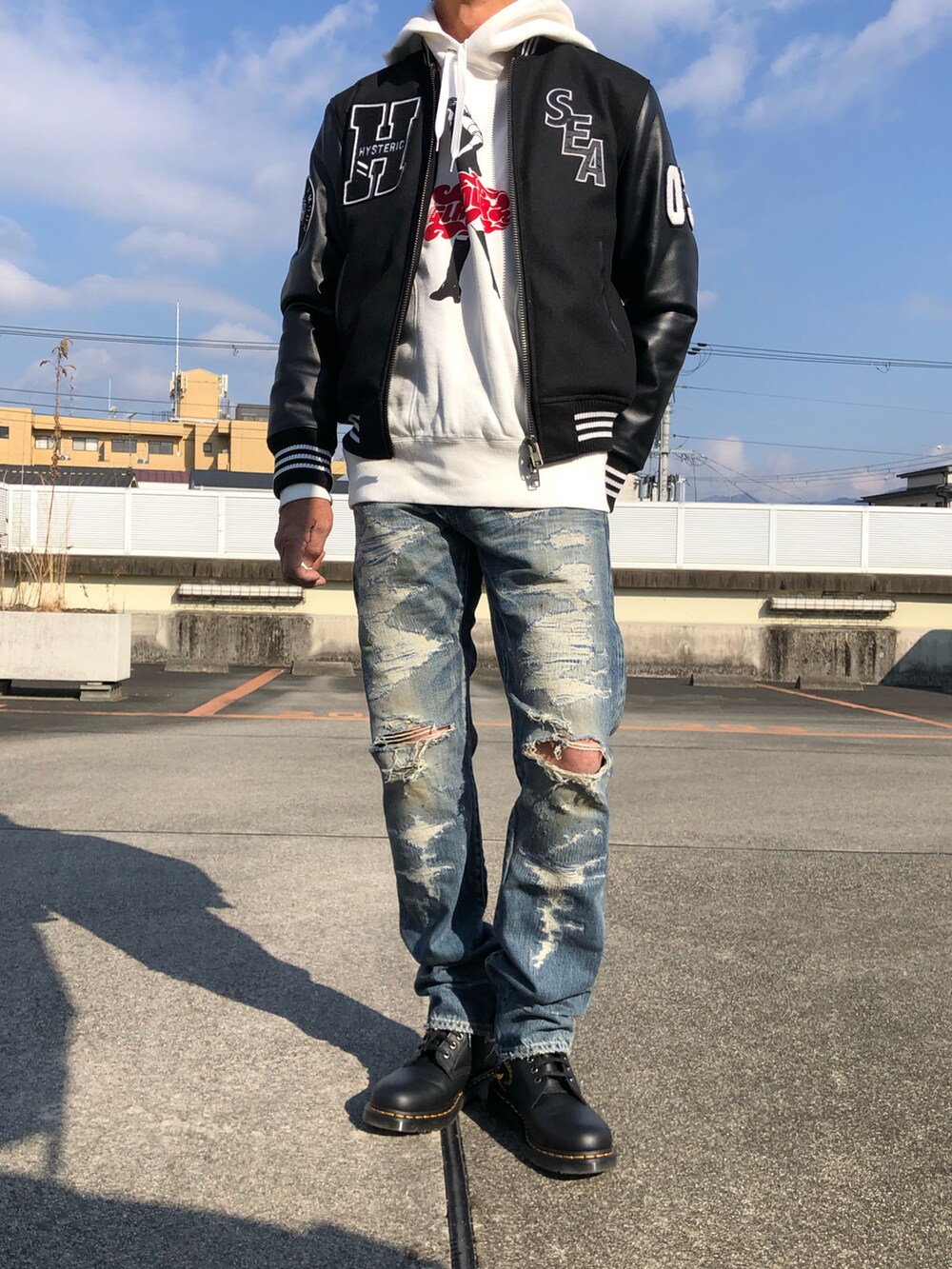 ブラック系のスタジャン、ホワイト系のパーカー、ブルー系のデニムパンツを着用したメンズの冬コーディネートの2枚目の写真