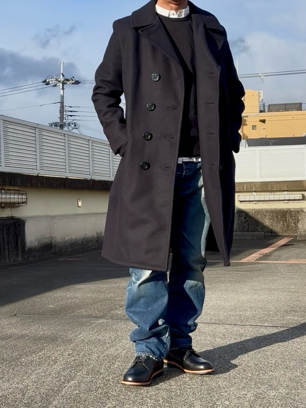 ブルー系のピーコート、ブラック系のブーツ、ブルー系のデニムパンツを着用したメンズの冬コーディネートの2枚目の写真