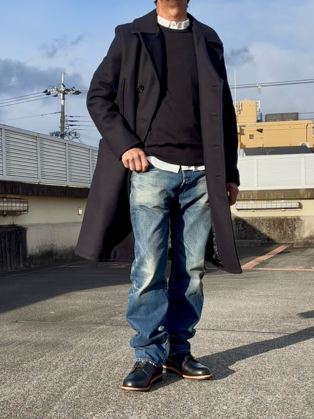 ブルー系のピーコート、ブラック系のブーツ、ブルー系のデニムパンツを着用したメンズの冬コーディネートの3枚目の写真