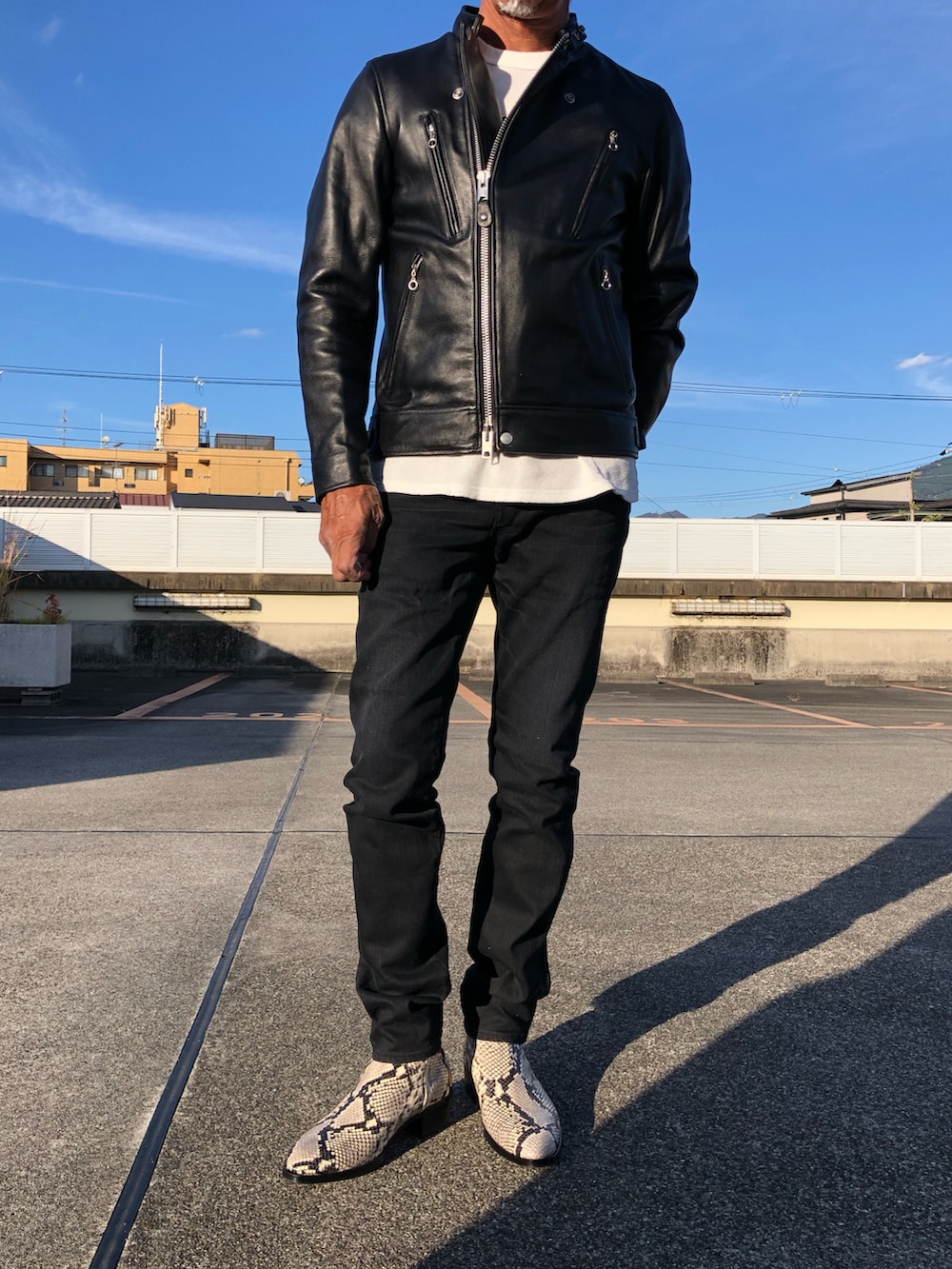 ブラック系のライダースジャケット、ホワイト系のスウェット、ベージュ系のブーツを着用したメンズの秋コーディネートの3枚目の写真