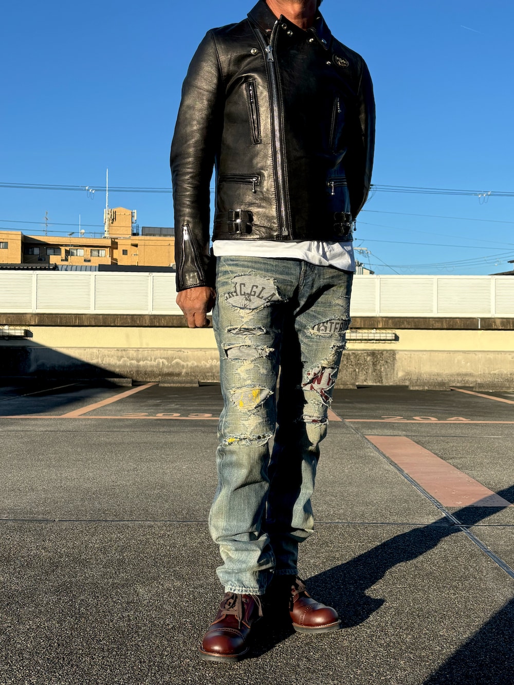 ホワイト系のTシャツ/カットソー、ブラック系のライダースジャケット、ブルー系のデニムパンツを着用したメンズの秋コーディネートの2枚目の写真