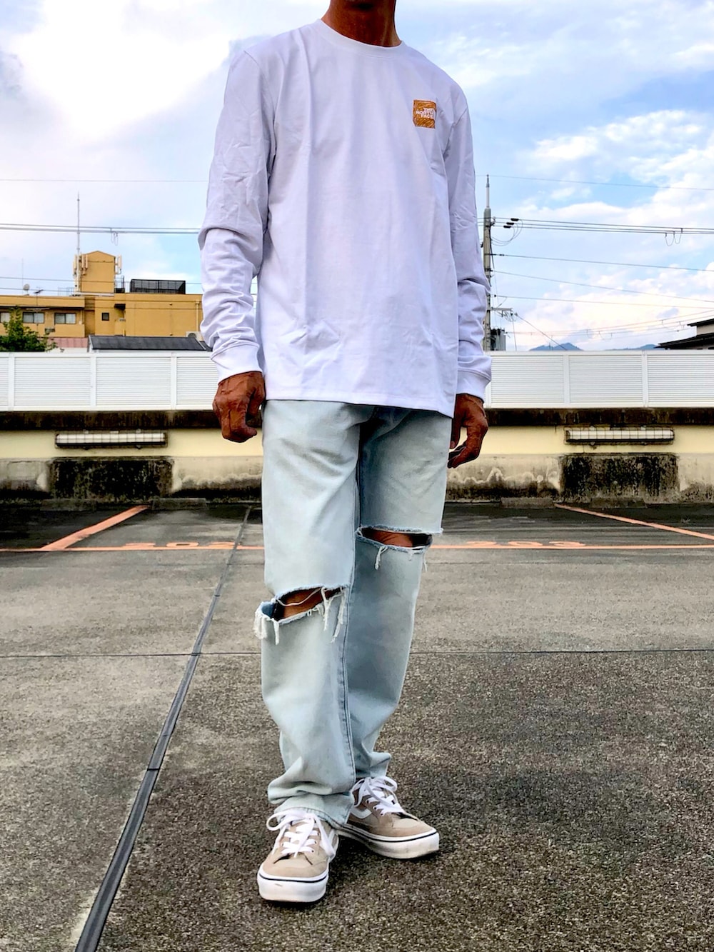 ホワイト系のTシャツ/カットソー、ブルー系のデニムパンツ、ベージュ系のスニーカーを着用したメンズの秋コーディネートの3枚目の写真