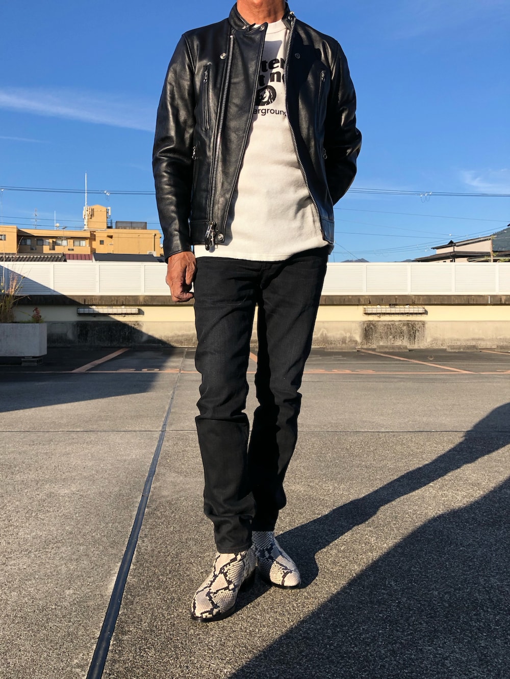 ブラック系のライダースジャケット、ホワイト系のスウェット、ベージュ系のブーツを着用したメンズの秋コーディネートの2枚目の写真