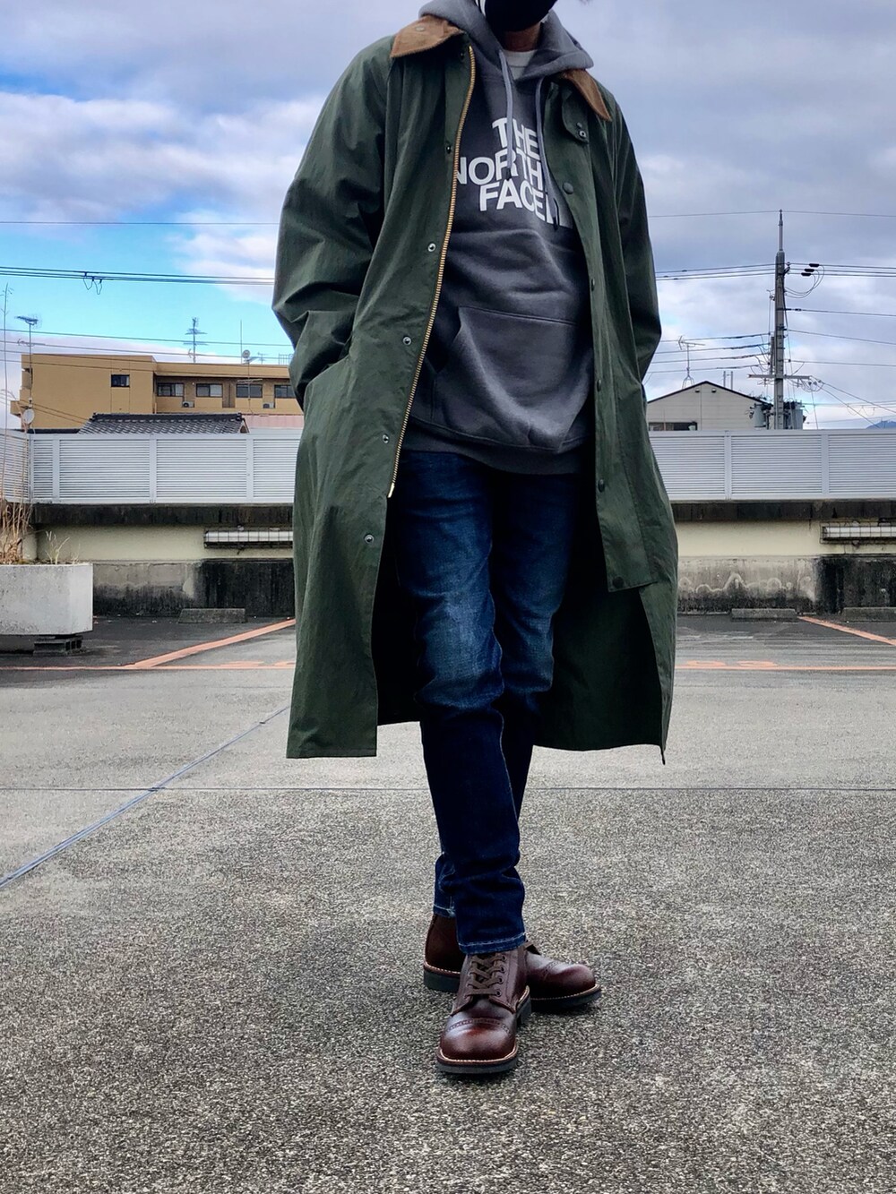 グレー系のパーカー、グリーン系のステンカラーコート、ブルー系のデニムパンツを着用したメンズの冬コーディネートの3枚目の写真