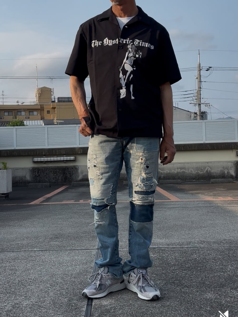 ブラック系のポロシャツ、ブルー系のデニムパンツ、グレー系のスニーカーを着用したメンズの夏コーディネートの2枚目の写真