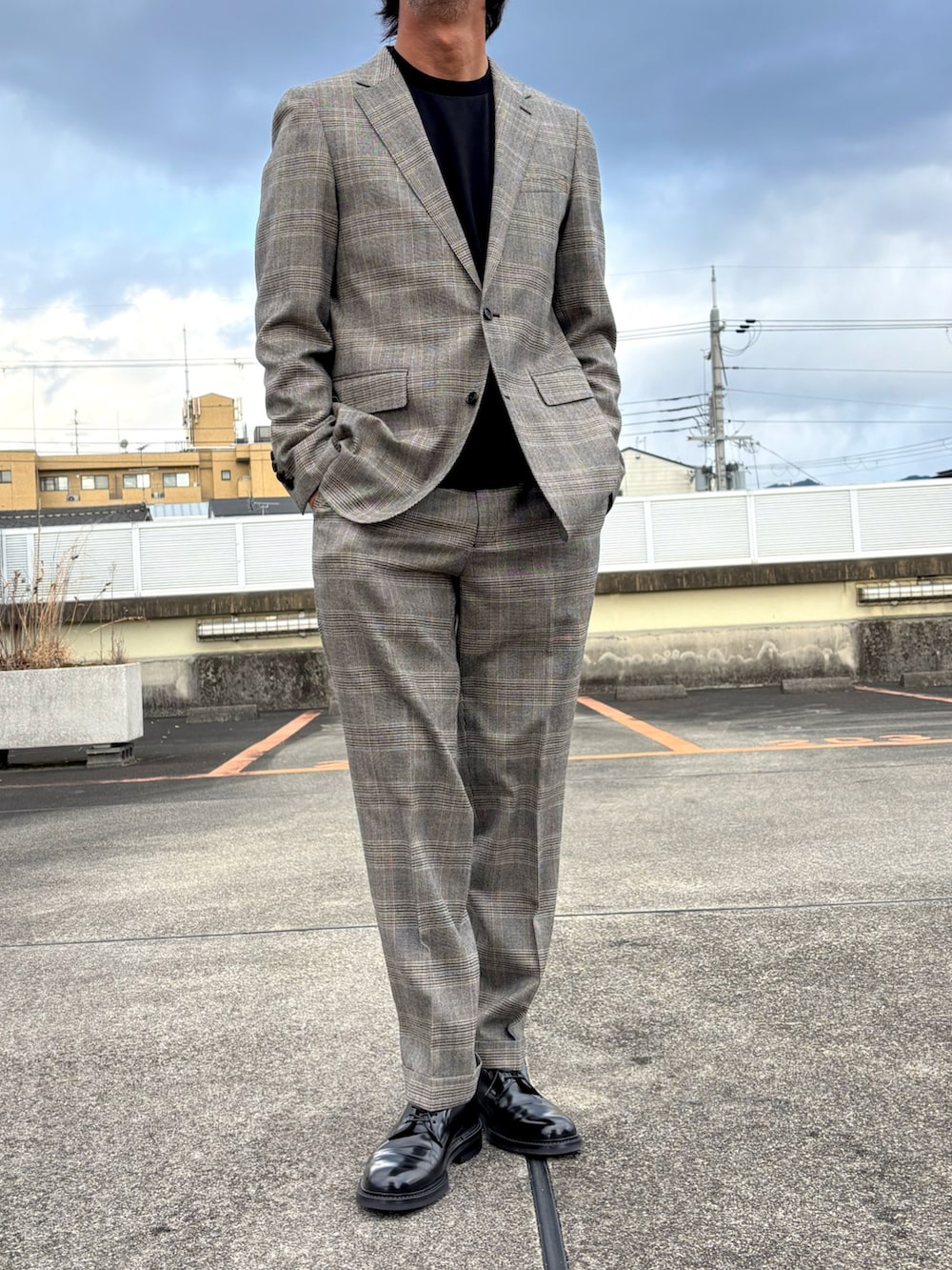 ブラウン系のスーツジャケット、ブラウン系のスーツパンツ、ブラック系のドレスシューズを着用したメンズの冬コーディネートの4枚目の写真