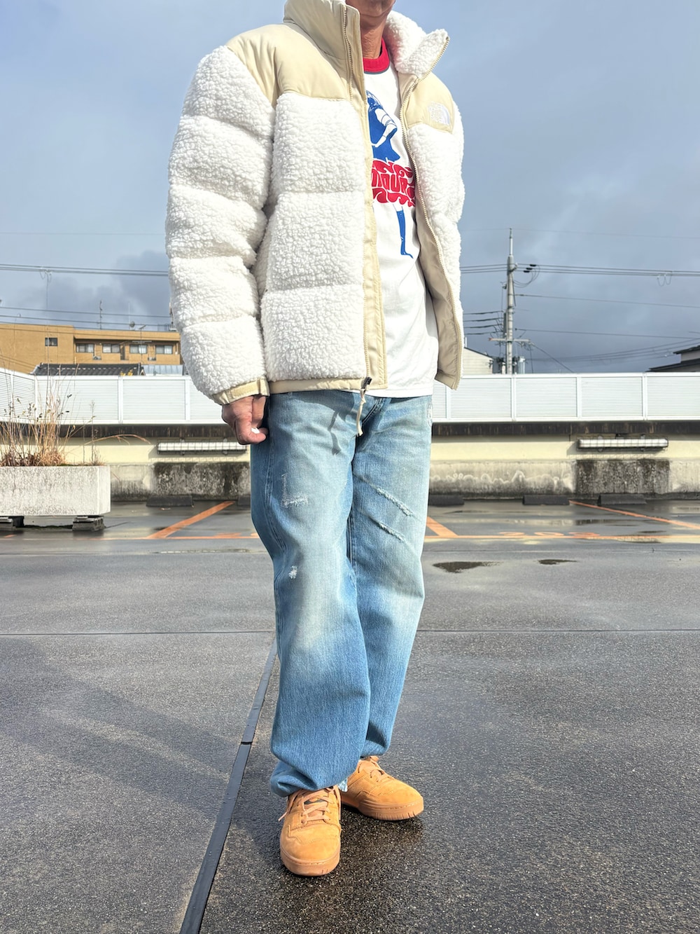 ホワイト系のダウンジャケット/コート、ホワイト系のTシャツ/カットソー、ブルー系のデニムパンツを着用したメンズの冬コーディネートの2枚目の写真