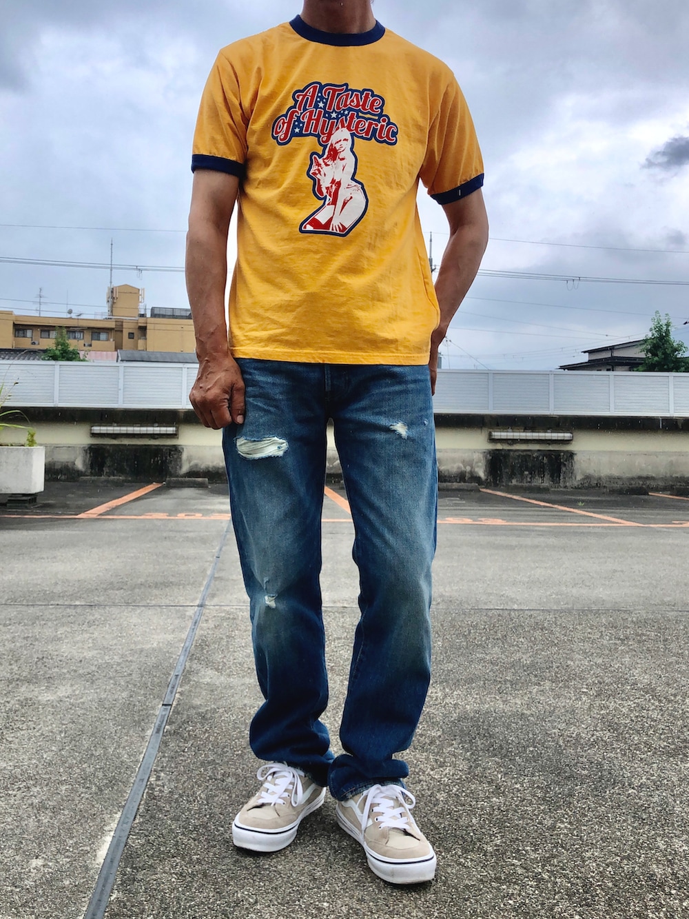 イエロー系のTシャツ/カットソー、ブルー系のデニムパンツ、ベージュ系のスニーカーを着用したメンズの夏コーディネートの2枚目の写真