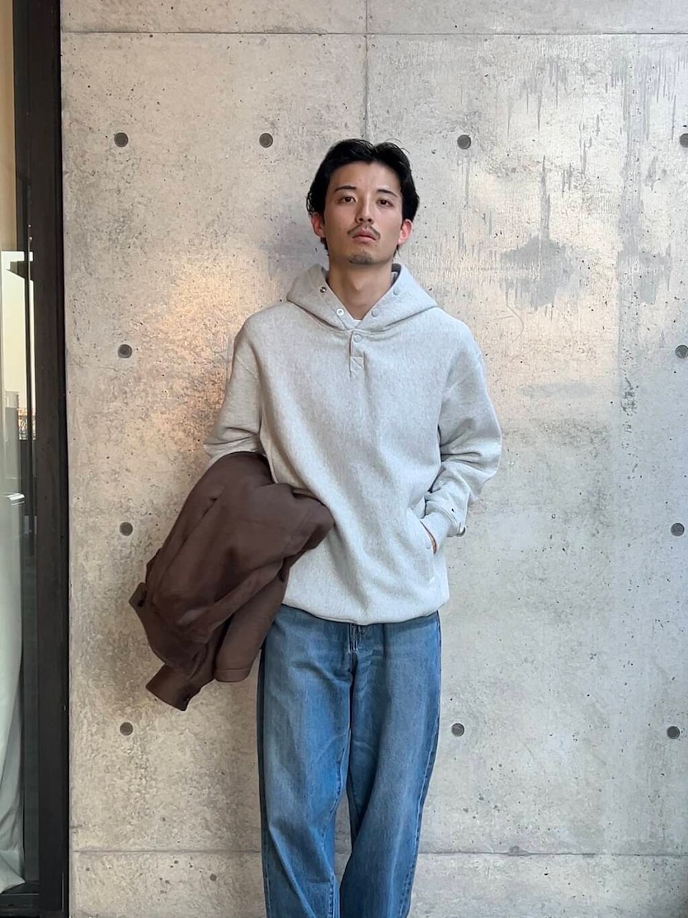 ベージュ系のスニーカー、ブルー系のデニムパンツ、グレー系のパーカーを着用したメンズの秋コーディネートの3枚目の写真