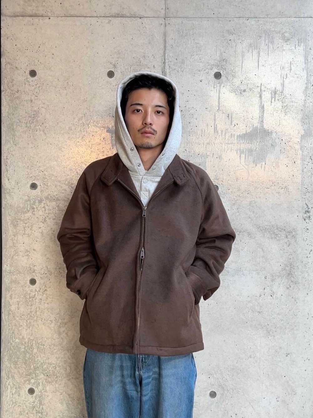 ベージュ系のスニーカー、ブルー系のデニムパンツ、グレー系のパーカーを着用したメンズの秋コーディネートの2枚目の写真