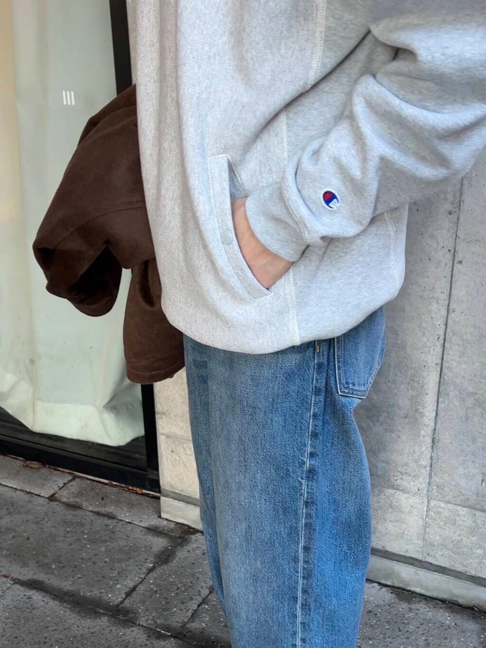 ベージュ系のスニーカー、ブルー系のデニムパンツ、グレー系のパーカーを着用したメンズの秋コーディネートの4枚目の写真