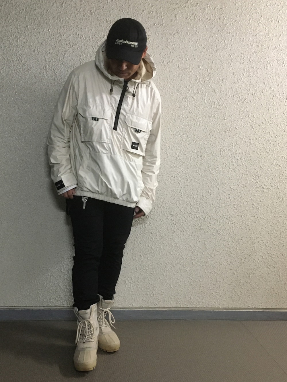 ベージュ系のナイロンジャケット、ブラック系のパンツ、ベージュ系のシューズを着用したメンズの春コーディネートの2枚目の写真