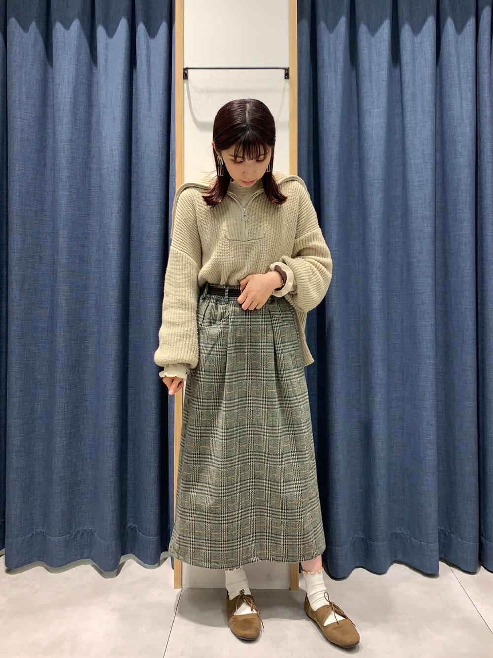 グレー系のスカート、ホワイト系のニット/セーター、ベージュ系のニット/セーターを着用したレディースの秋コーディネートの2枚目の写真