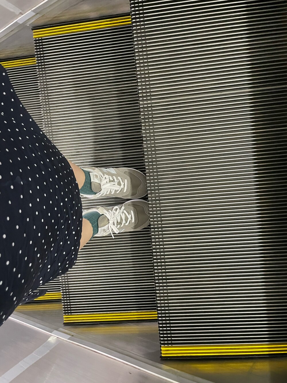 ベージュ系のトートバッグ、ブラック系のワンピース、グレー系のスニーカーを着用したレディースの夏コーディネートの2枚目の写真